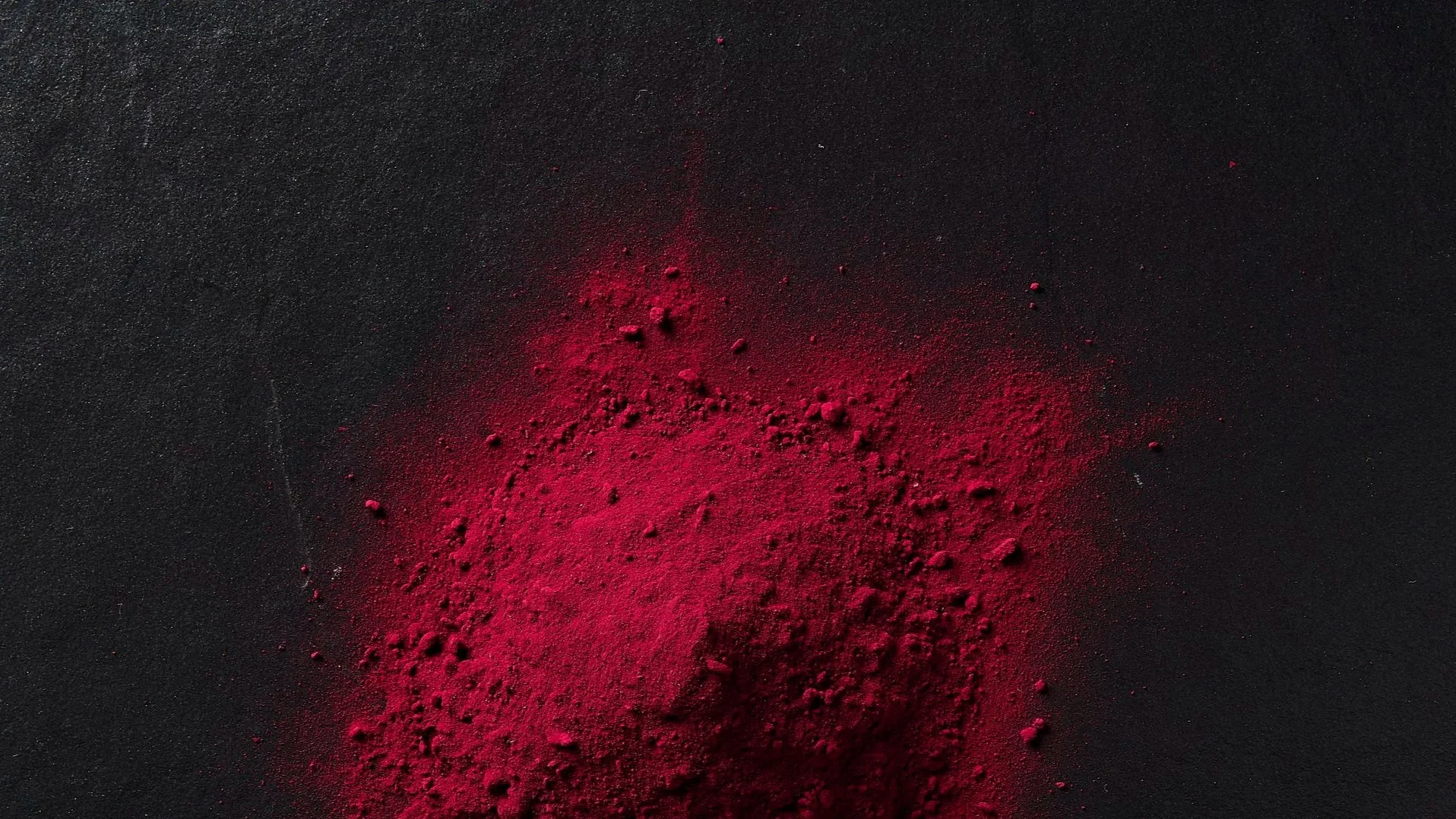 Red powder scattered on a black textured surface.