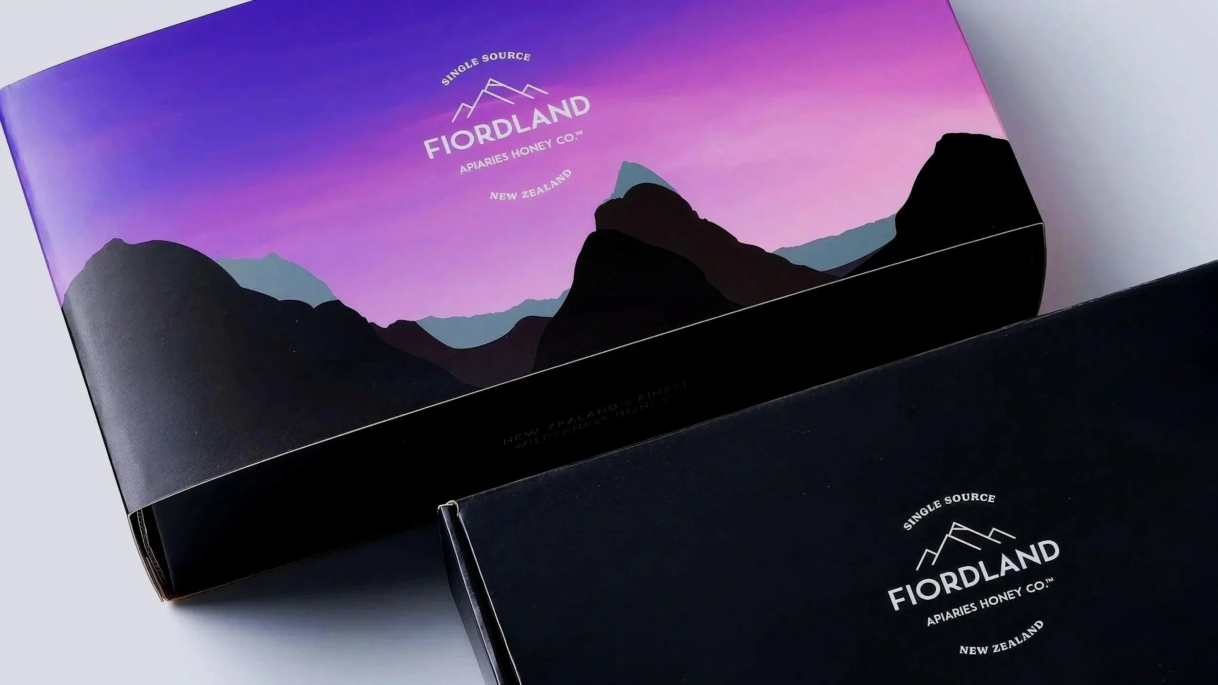 A box of Fiordland single source New Zealand honey with mountain and sunset design on the packaging.