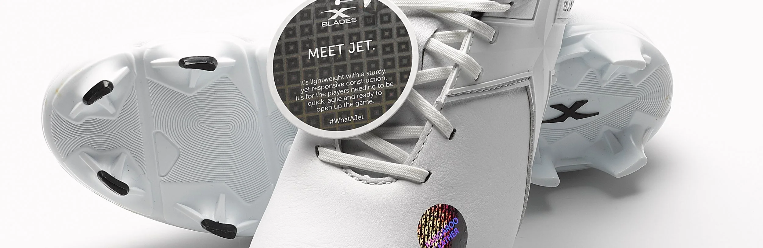 White athletic sneaker with black accents, featuring a tag that says 'Meet Jet' and other informational text about the shoe, displayed upside down.