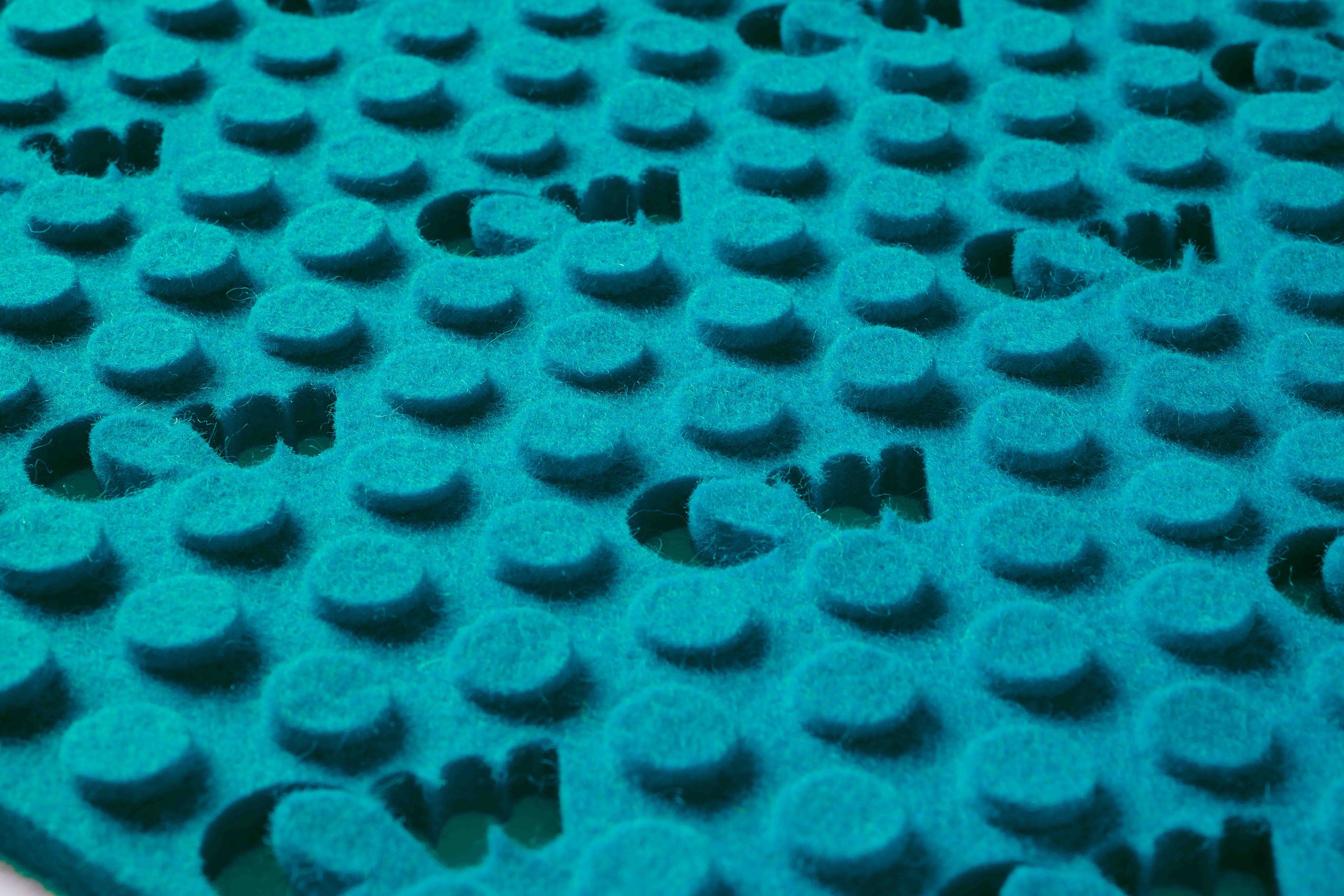 Close-up of a teal oceanwool material with evenly spaced, circular raised dots