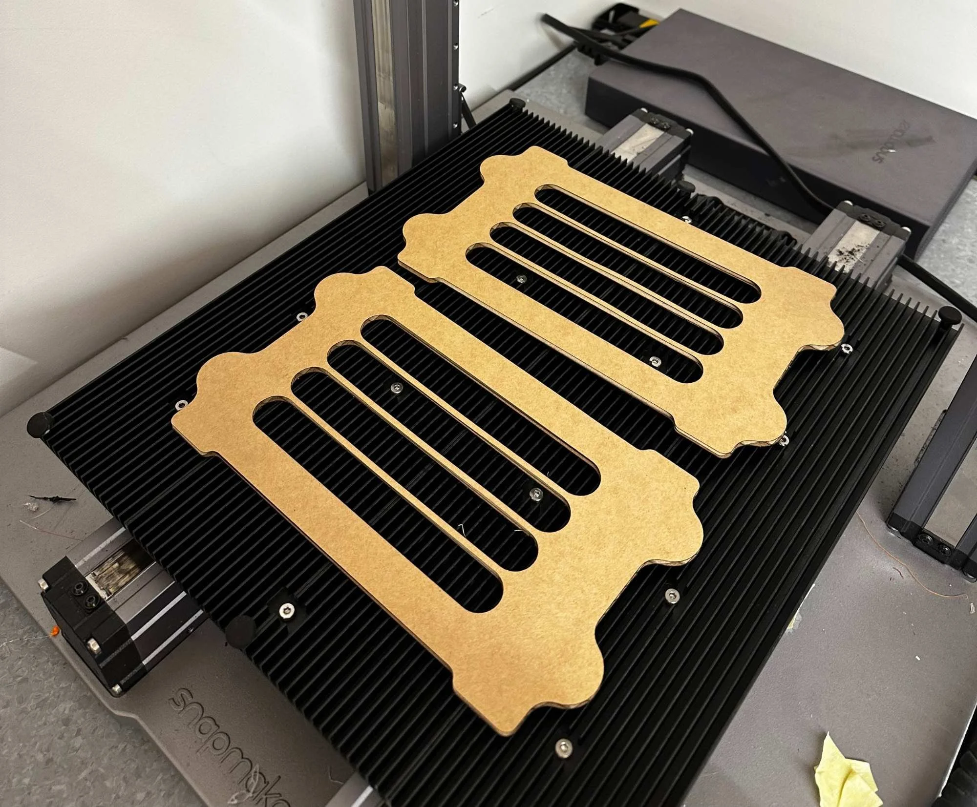 A laser-cut wooden guitar body template on top of an industrial laser cutter machine.
