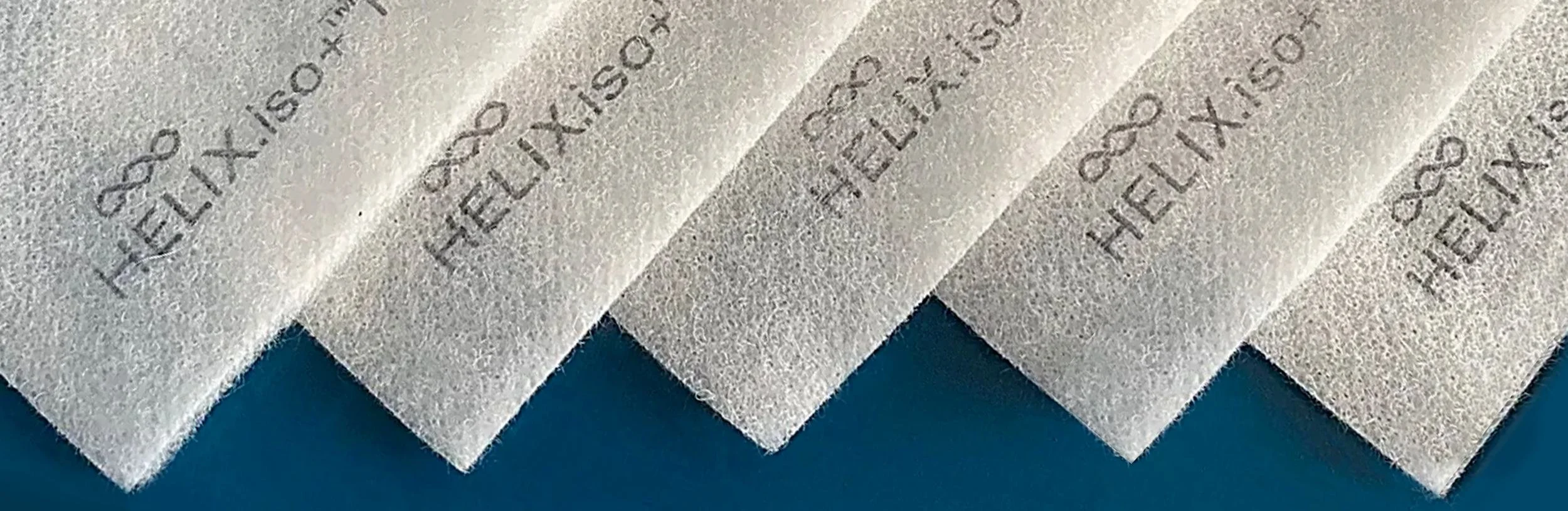 A close-up of several white filter papers with the word 'HELIX' and some numbers printed in black ink on them, arranged overlapping on a blue surface.