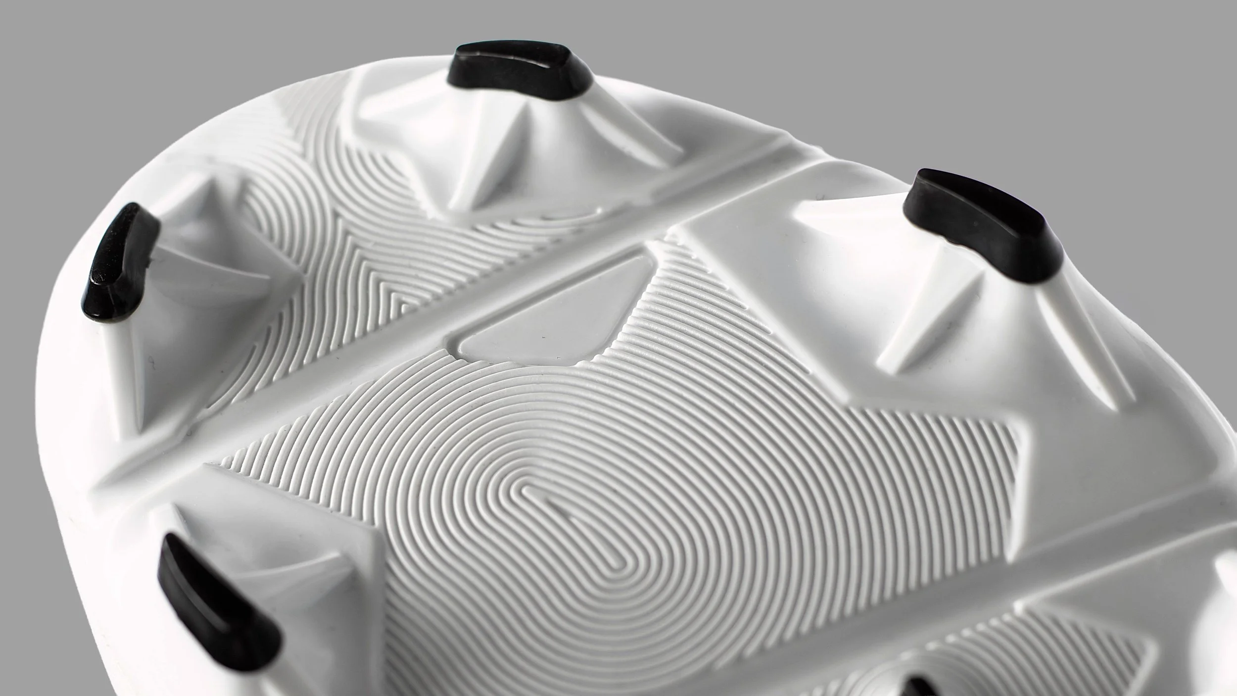 Close-up of the bottom of a white athletic shoe, showing black accents and textured sole patterns.