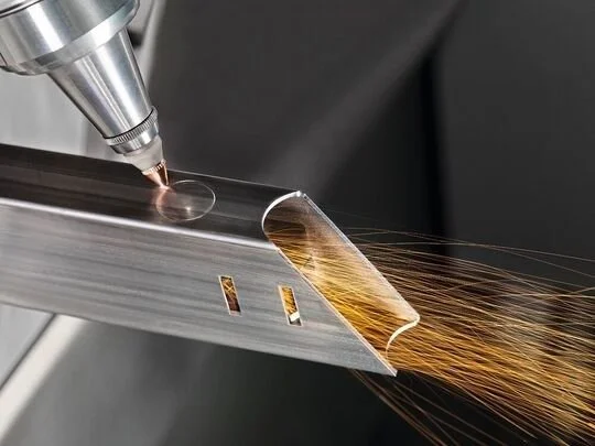 A close-up of a metal cutting process with sparks flying as a welding or machining tool works on a metal surface.