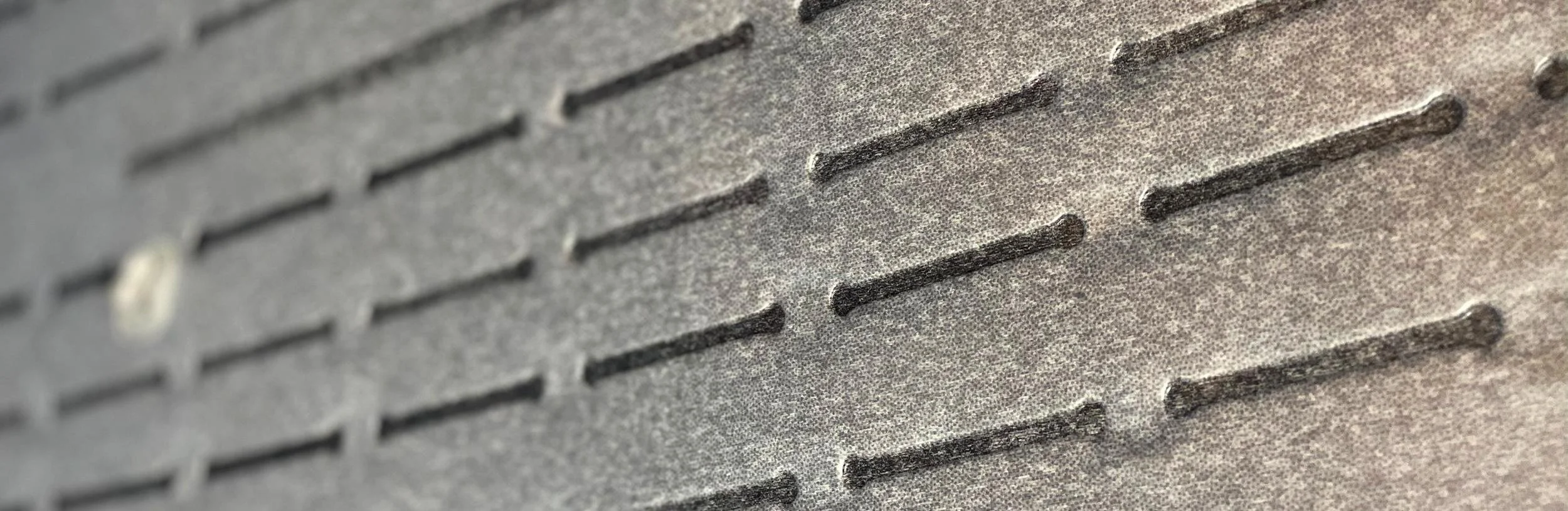 Close-up of textured gray surface with evenly spaced elongated raised lines.