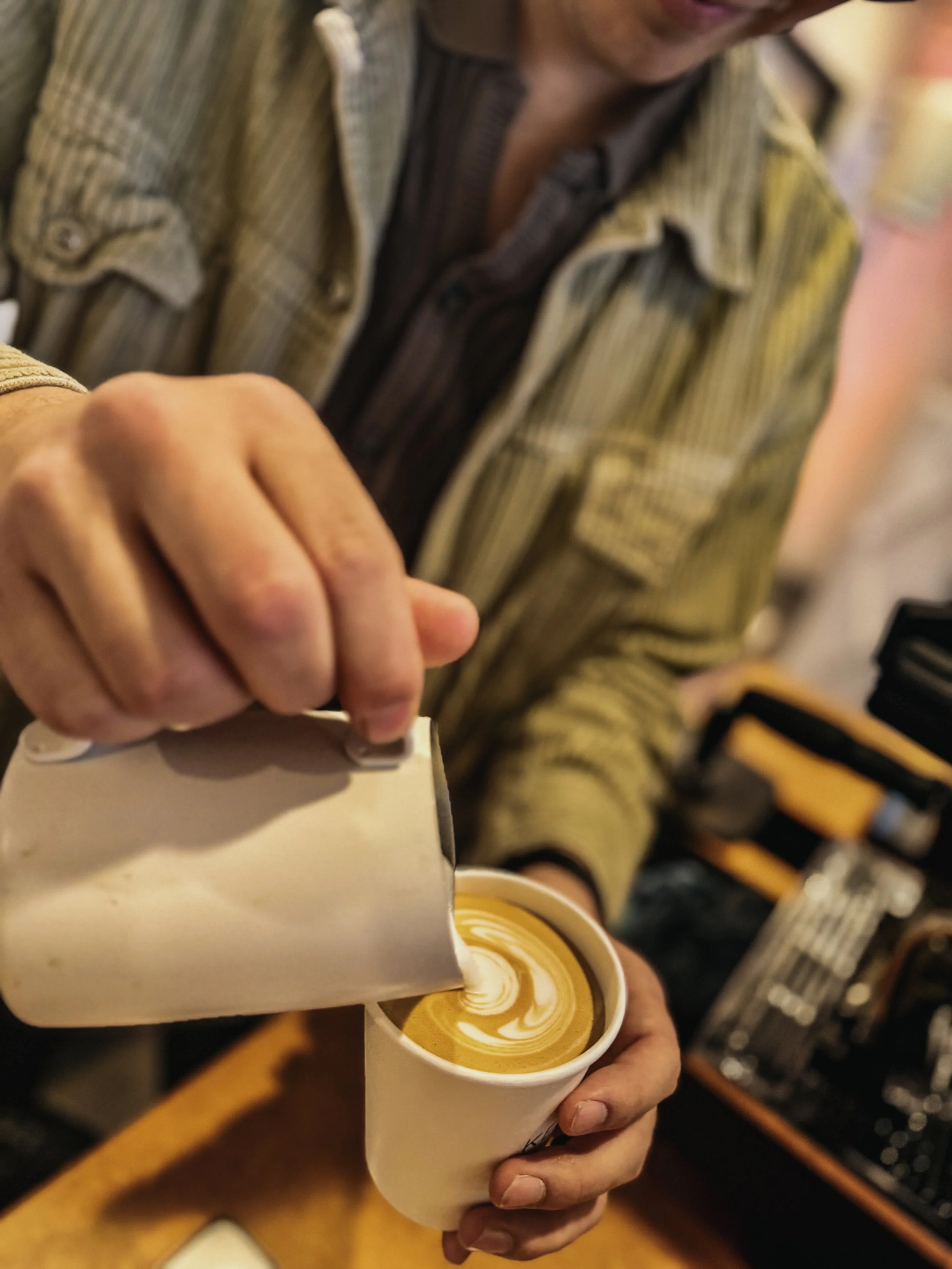 Person pouring steamed milk into a cup of coffee to make latte art.