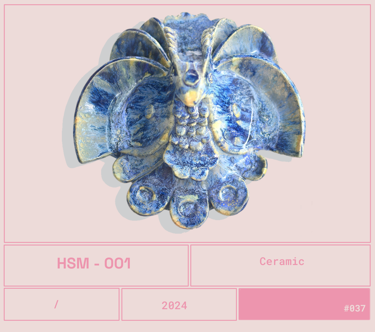 Escultura de cerámica que representa un elefante con elementos decorativos en tonos azules y dorados, en un fondo rosa claro.