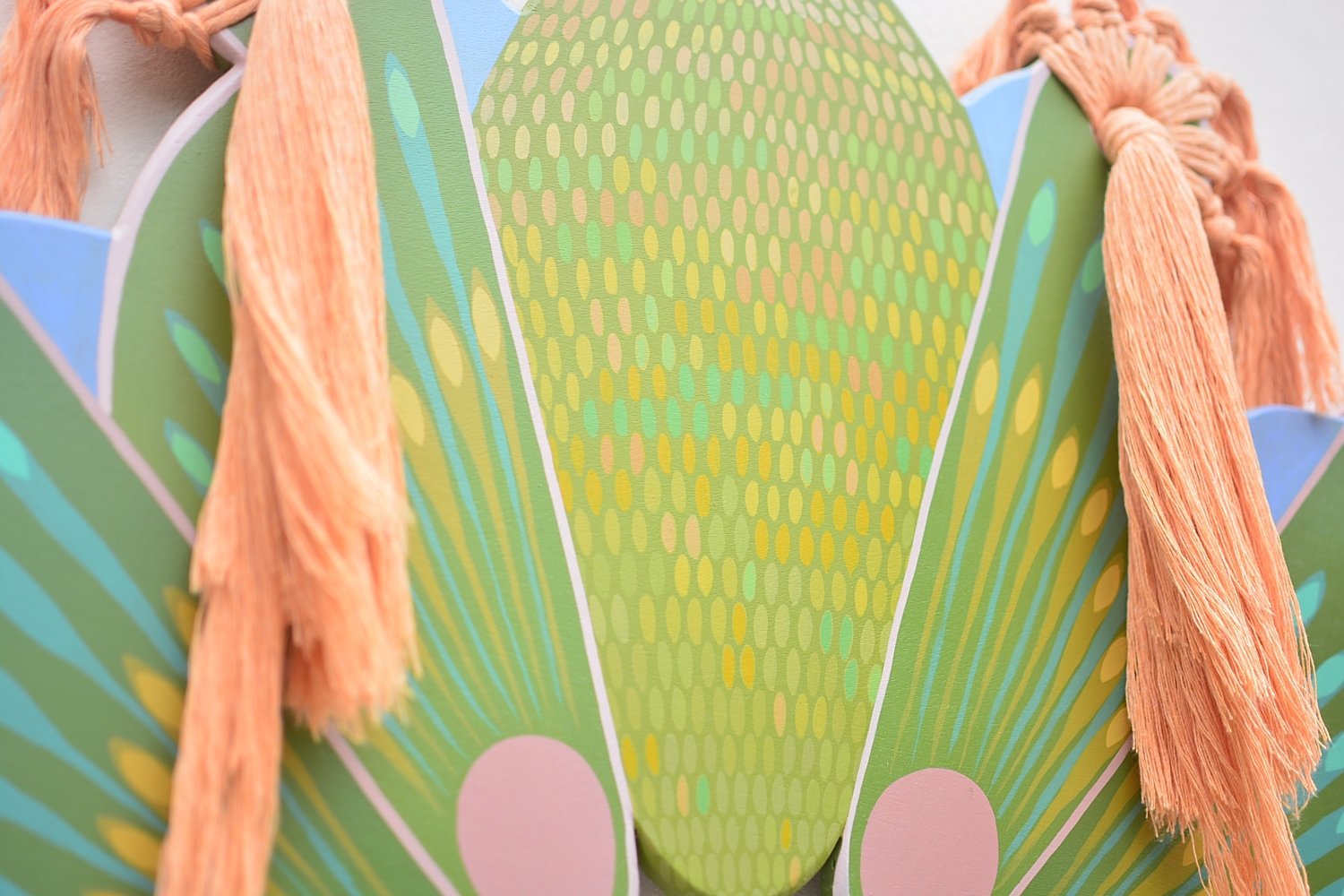 Enfoque en la cabeza y las alas de una mariposa de colores vivos, con detalles en tonos verdes, rosados y azules, y antenas de hilo de color naranja.