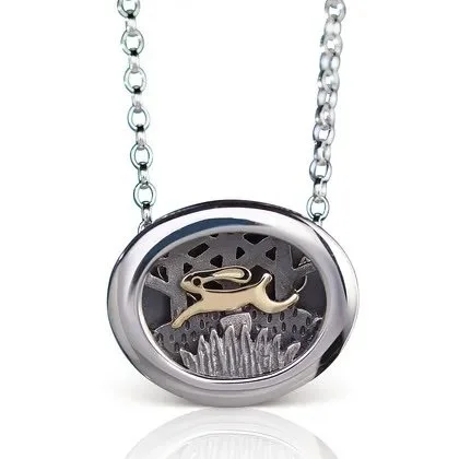 Silver necklace with oval pendant featuring a gold-colored whale shape inside and a decorative background.