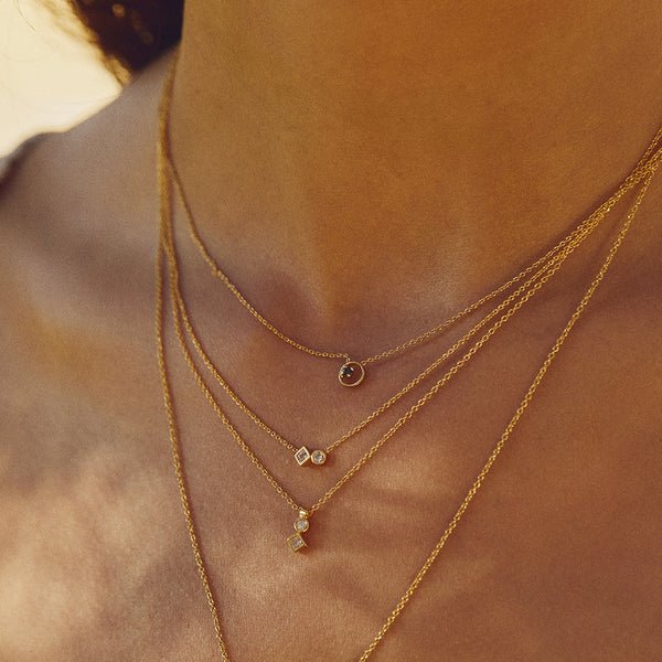 Multiple layered gold necklaces with various pendant designs on a woman's neck and chest.