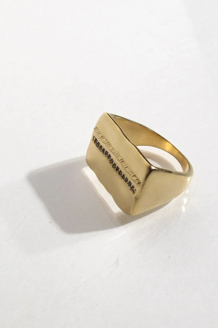 Gold ring with small black stones on a white surface