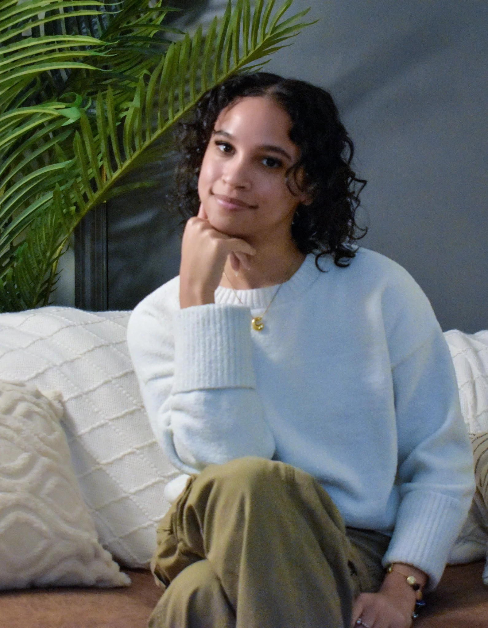 Young female therapist wearing a white sweater sits on a couch and smiles.