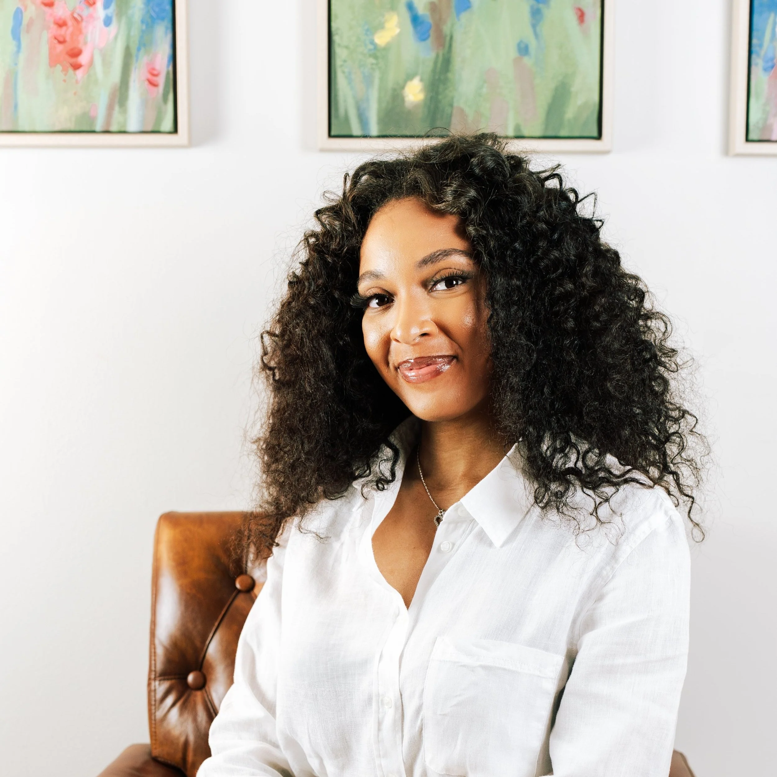 Black female therapist wearing a white shirt smiles at camera