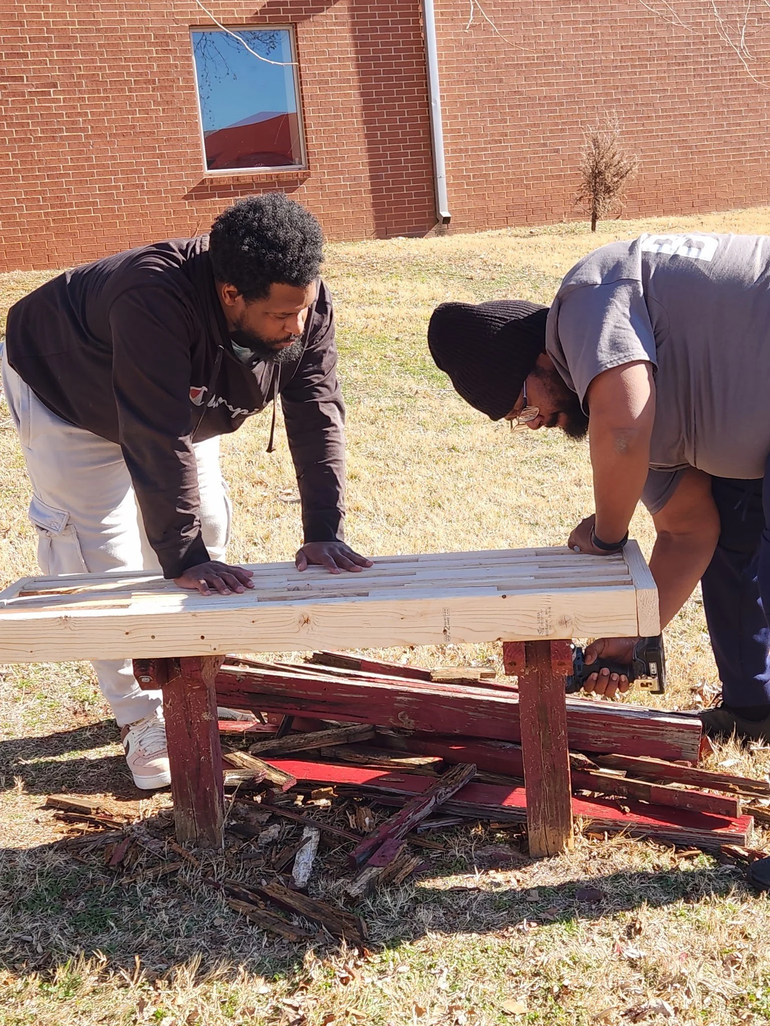 CNA Rayvon and client Marcus work together as part of the OKFD Men's Group to repair a bench and improve our community grounds
