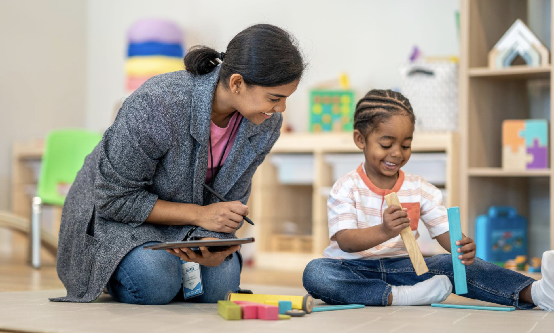 Occupational therapist working with a young child during a therapy session, using hands-on activities and educational toys to develop fine motor skills, sensory processing, and independence in a supportive environment.