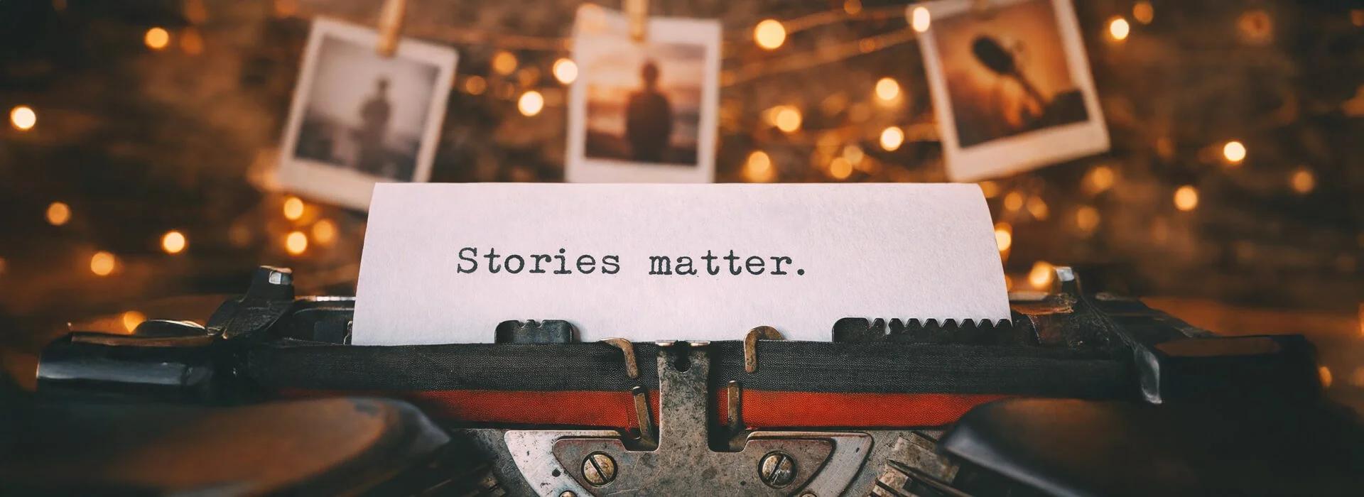 Typewriter close up with the words Stories matter on paper and warm lights in the background