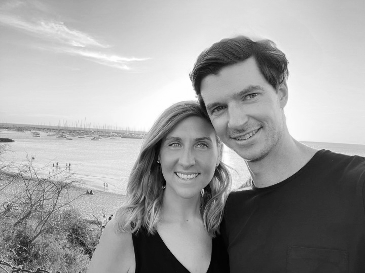 Black and white photo of Tahlia Belcher and Peter Fowler smiling together by the beach