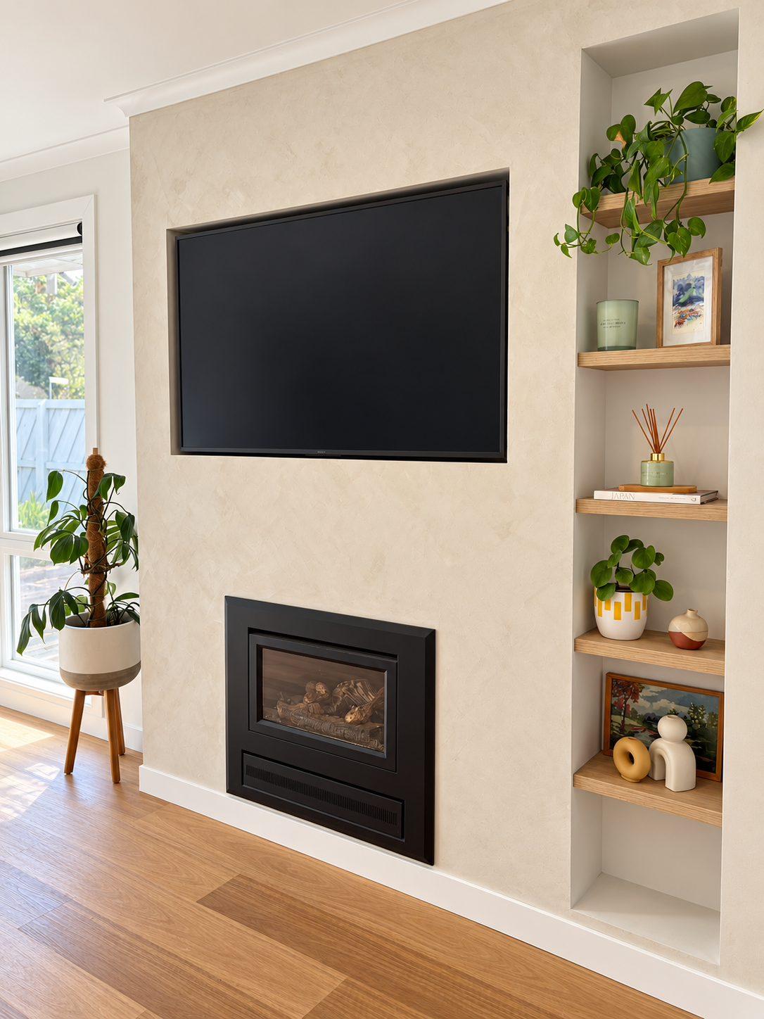 Mungari living room feature wall with limewash render, gas fireplace, wall-mounted TV and styled oak niche shelving