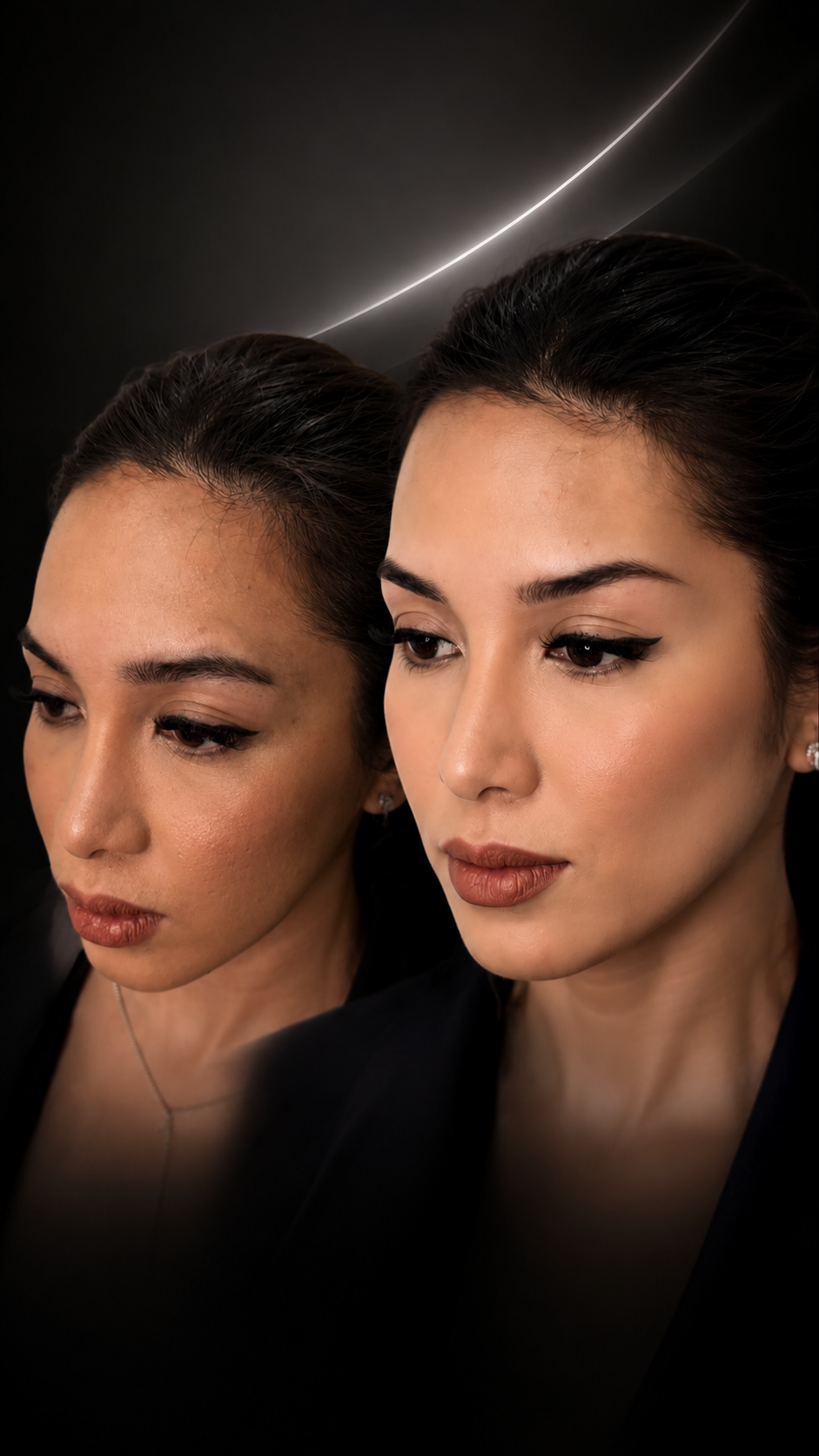 Close-up of two women with dark hair and makeup, reflected in a mirror with a diagonal light streak in the background.