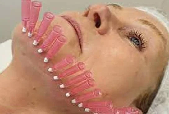 Close-up of a woman with pink hair rollers and pearl earrings, lying on a bed.
