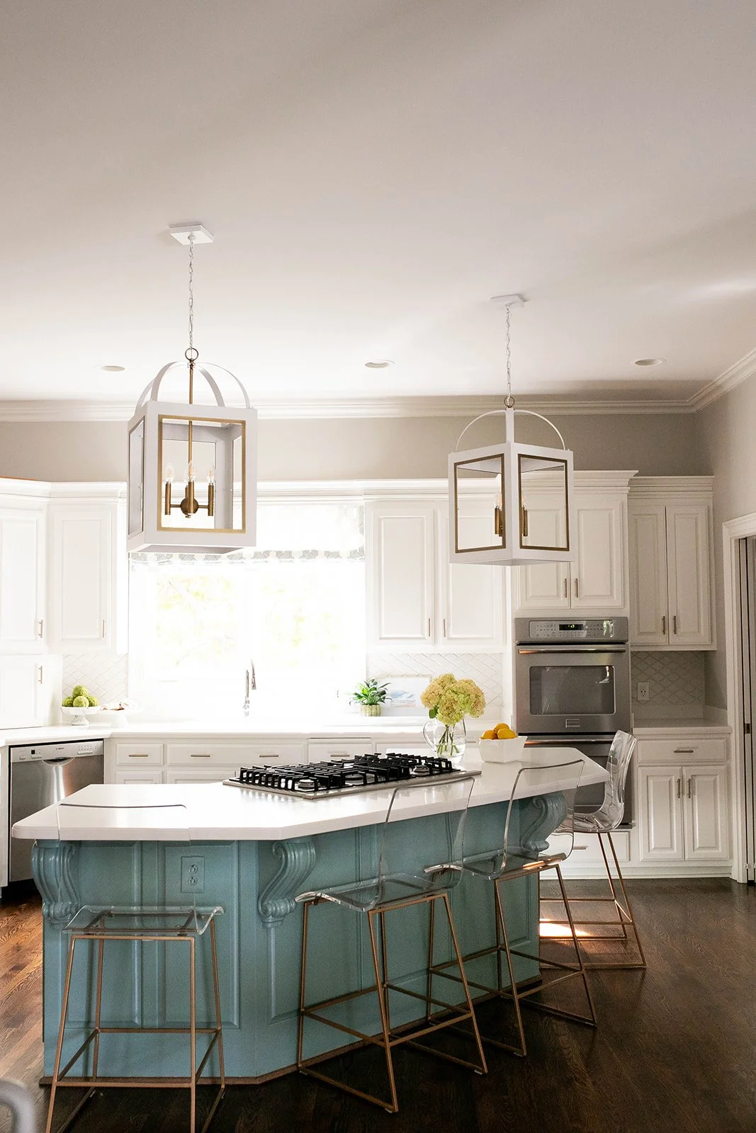 Modern kitchen with white cabinets, a large island with a blue base, bar stools, and pendant lights.