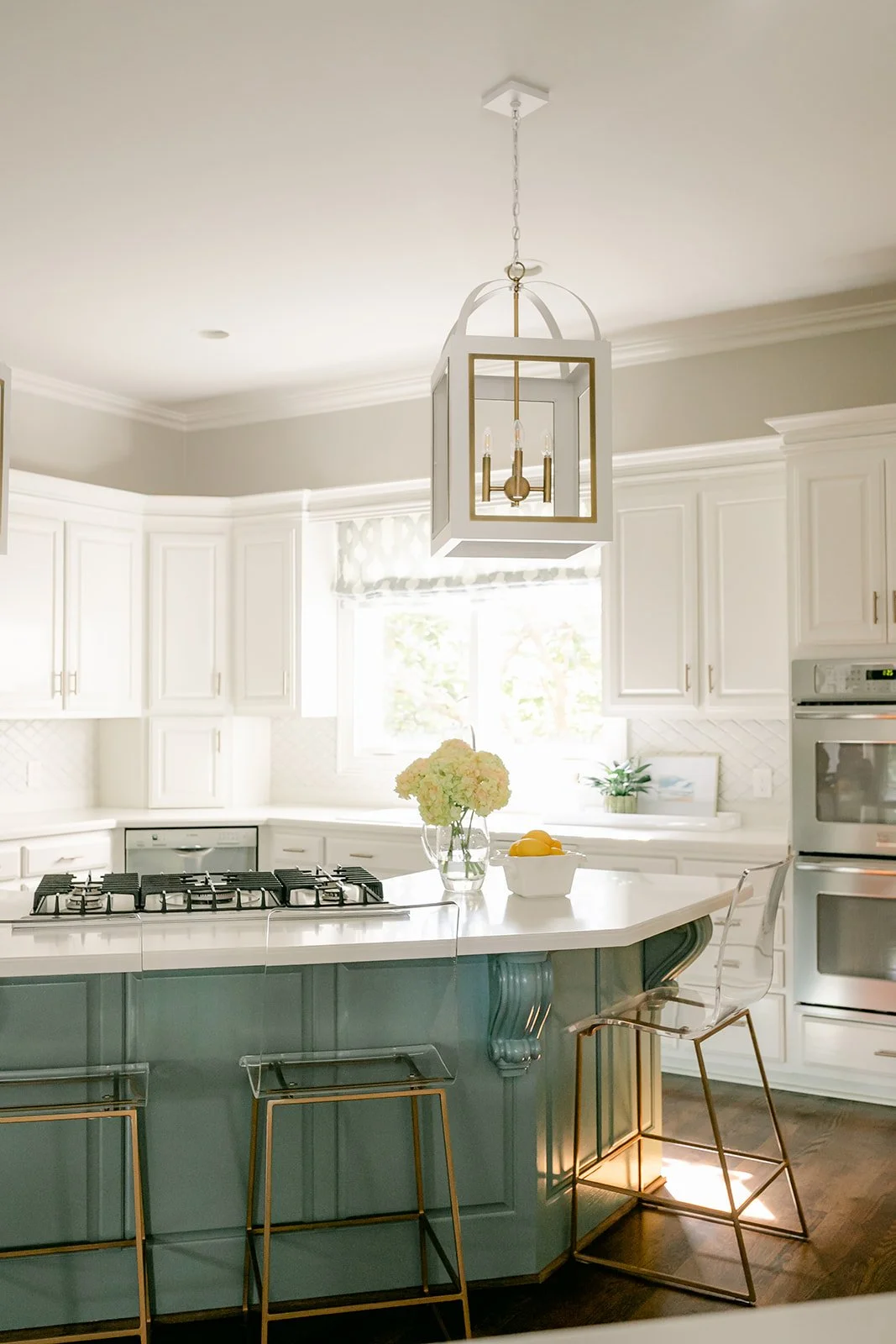 Modern kitchen with white cabinets, island with gas stove, pendant lighting, and acrylic bar stools.