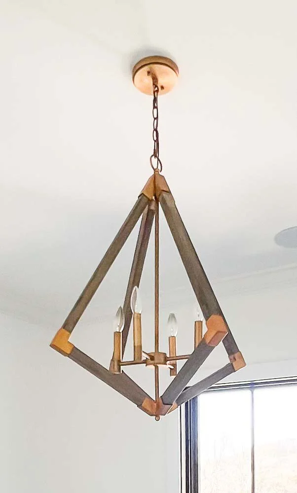 Geometric wooden chandelier with exposed bulbs hanging from a ceiling.
