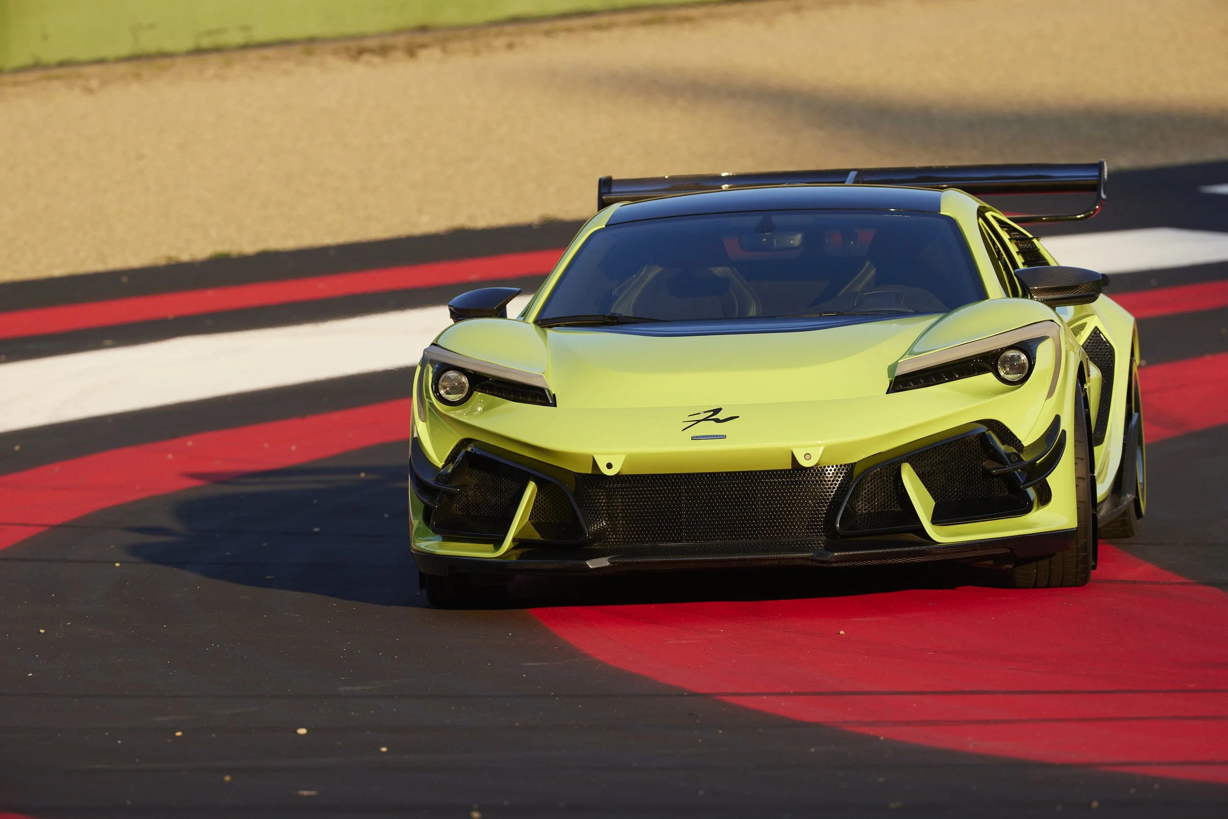 Auto sportiva gialla su pista con curve rosse e bianche.
