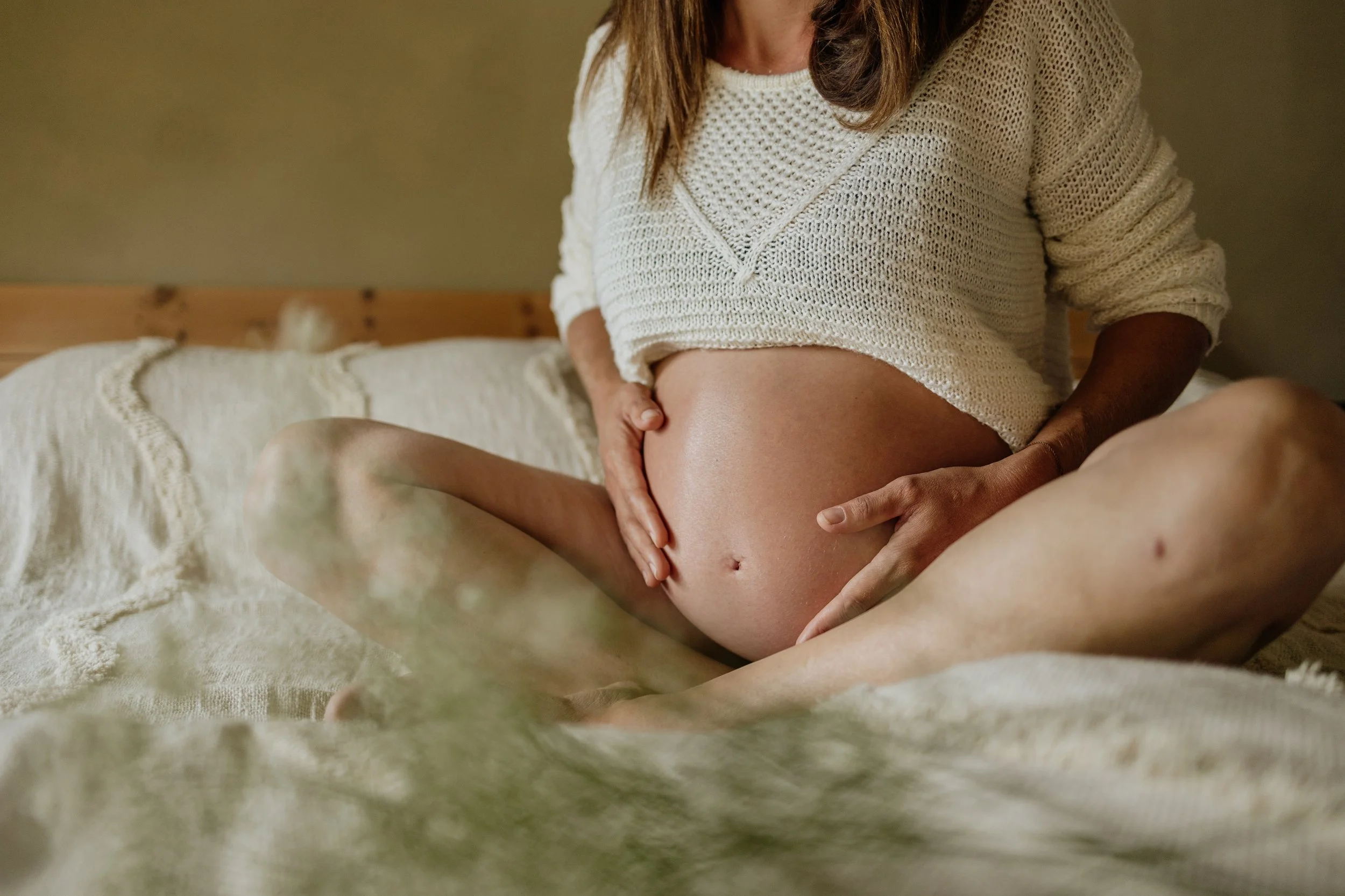 Babybauch haltend im Bett sitzend Montafon