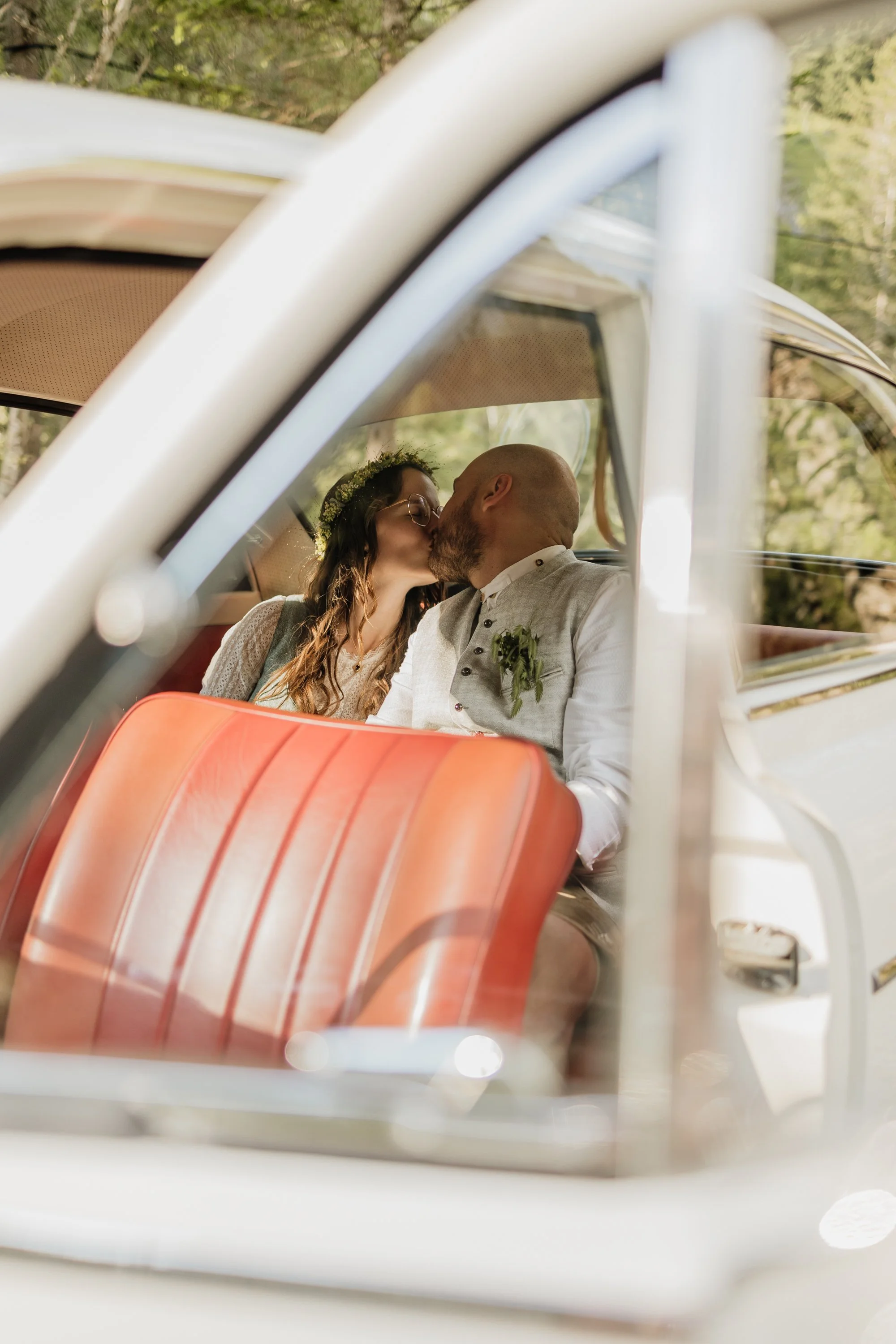 Hochzeitspaar im Auto küssend durch die Tür