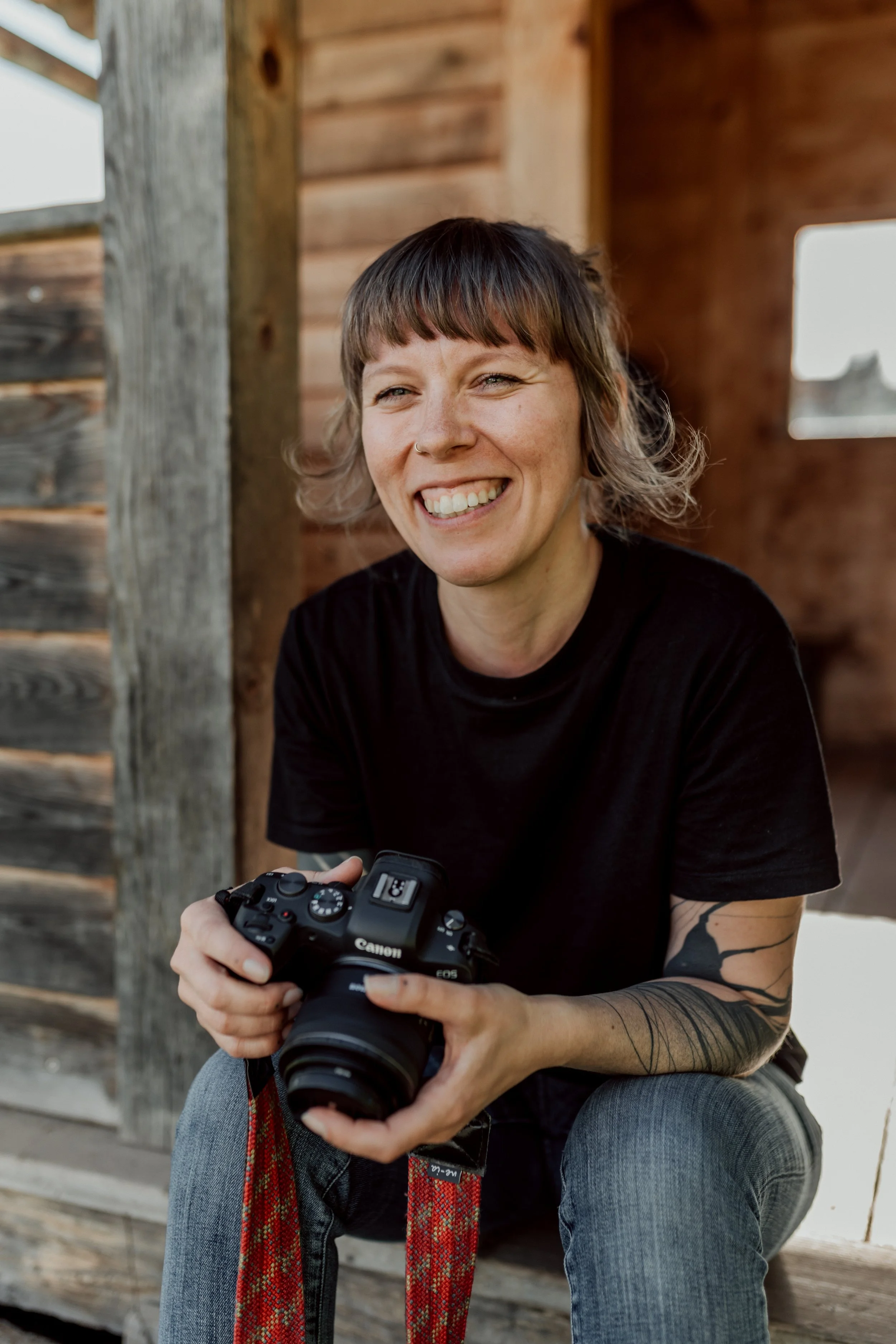 Fabienne Merkel Fotografin im Montafon Vorarlberg mit Kamera in der Hand lachend in die Kamera