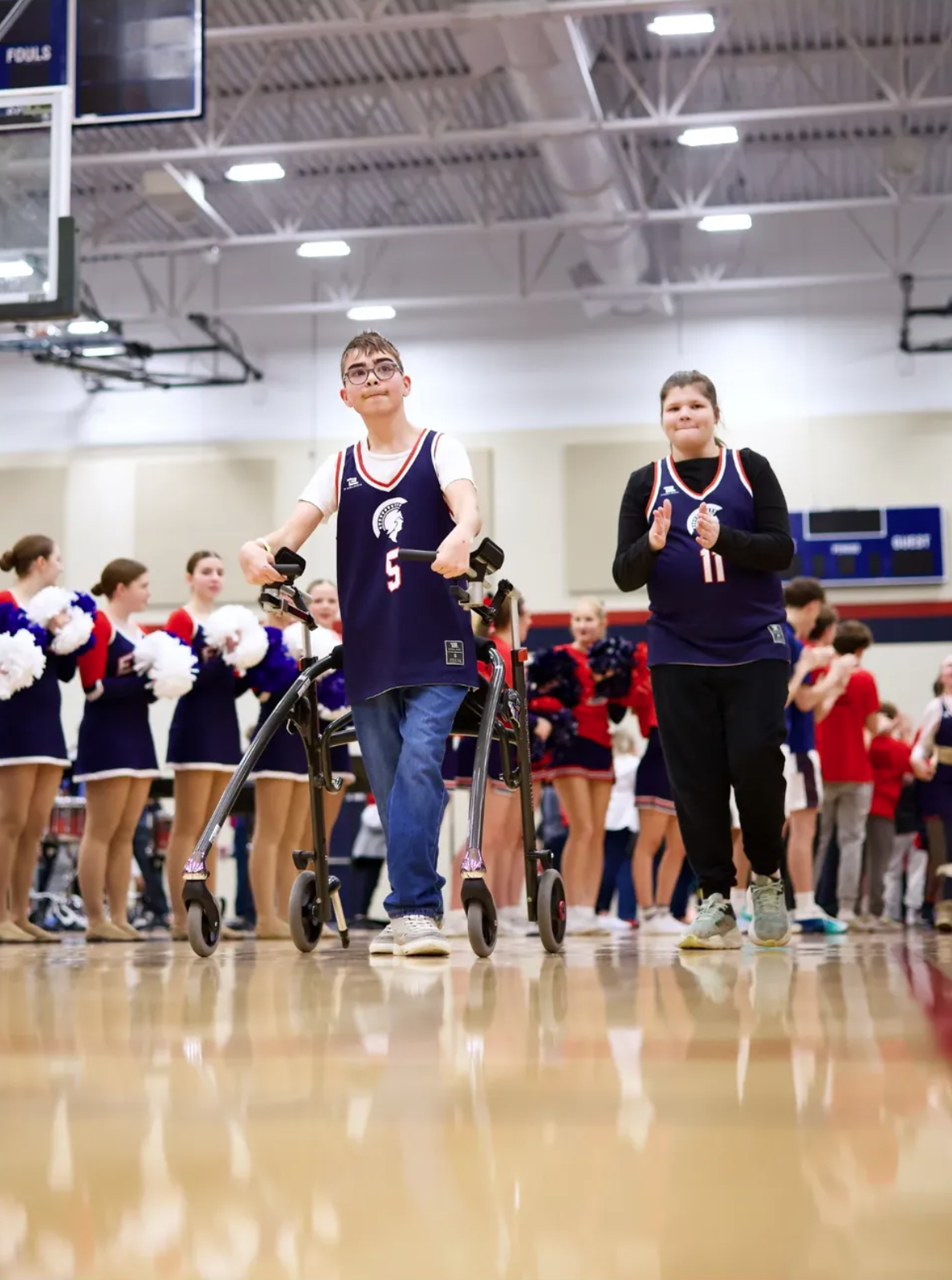 Two Unified sports athletes walking through a row of cheerleaders