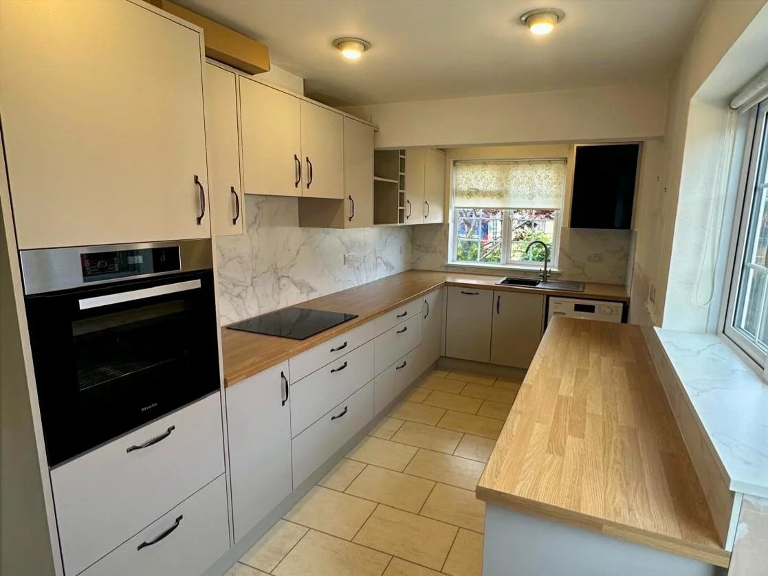 Kitchen with off-white cabinets, wooden countertops and black appliances.
