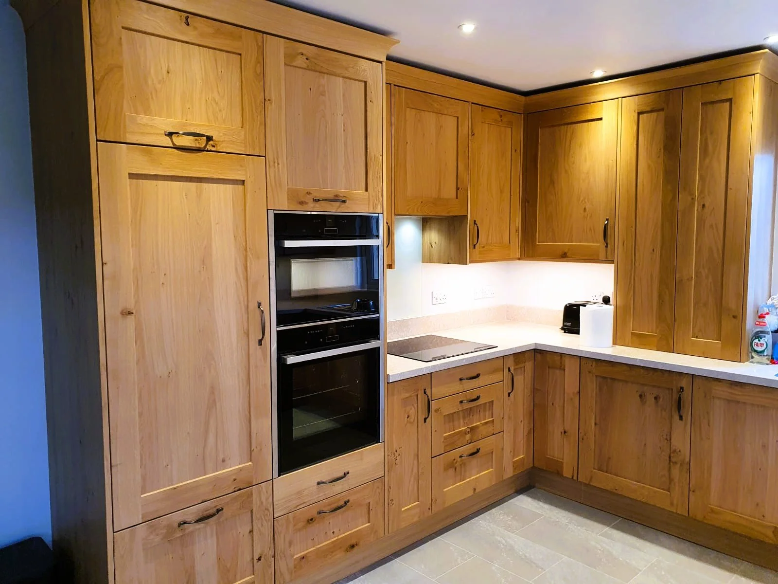 Kitchen with wooden cabinets, white countertop and built in oven.