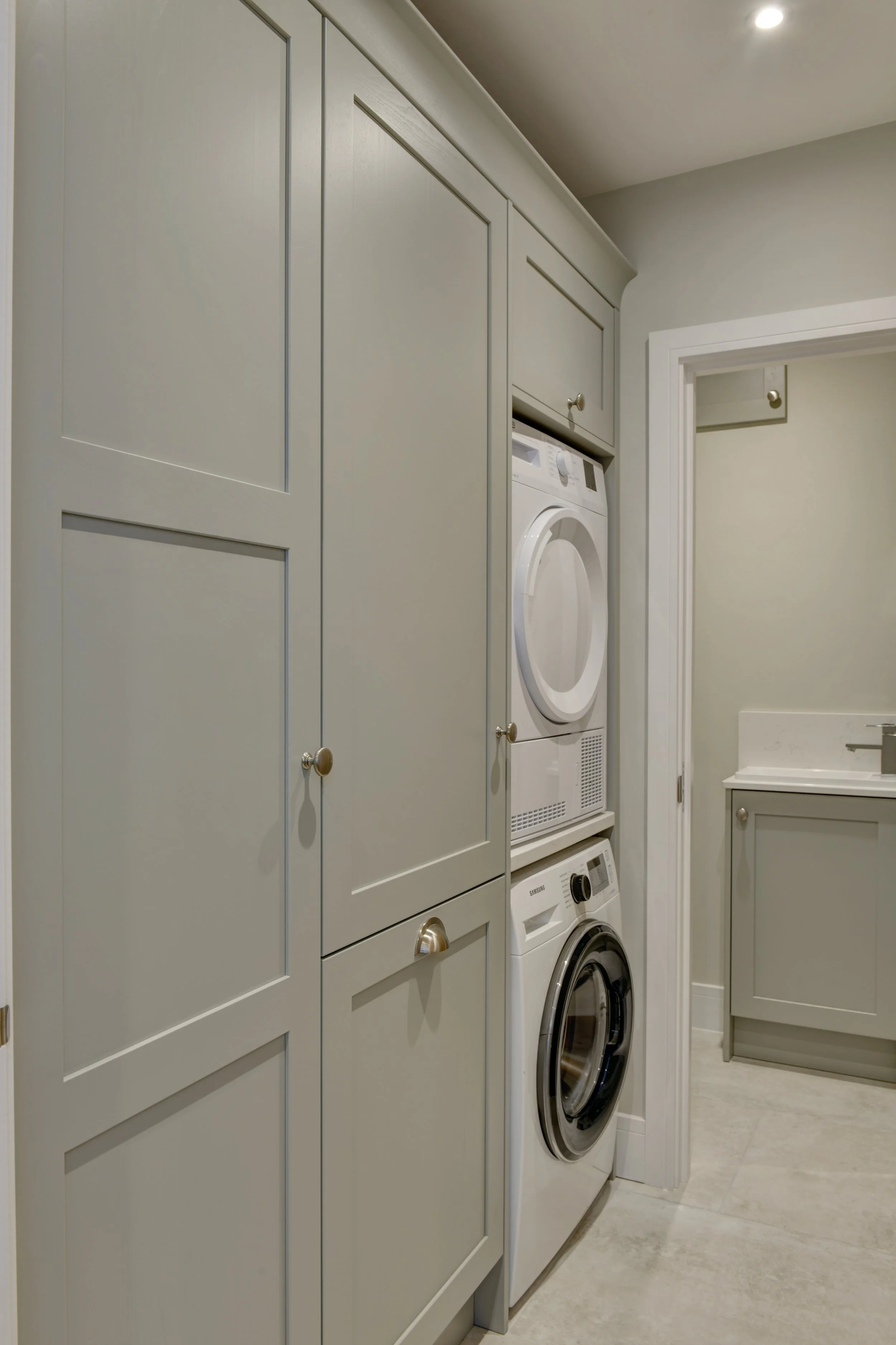 A laundry room with cream cabinetry and a front-loading washing machine and dryer stacked vertically.