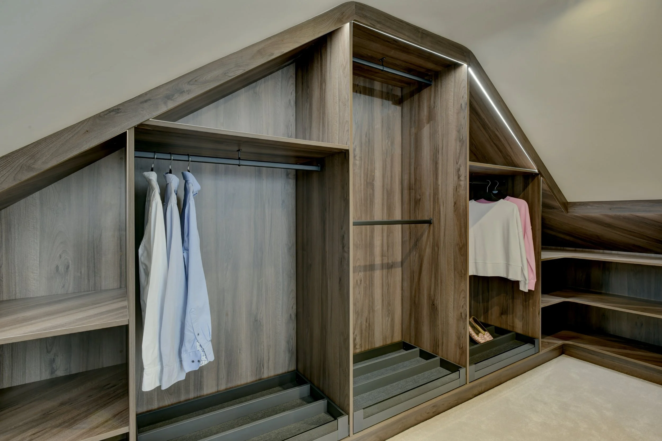 Custom walk-in closet with wooden shelving and drawers, featuring hanging space with clothes and shoes.