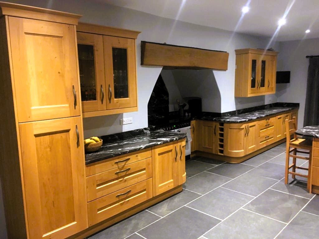 Traditional Kitchen with wooden cabinets, black granite countertops, and a black stove hood. 
