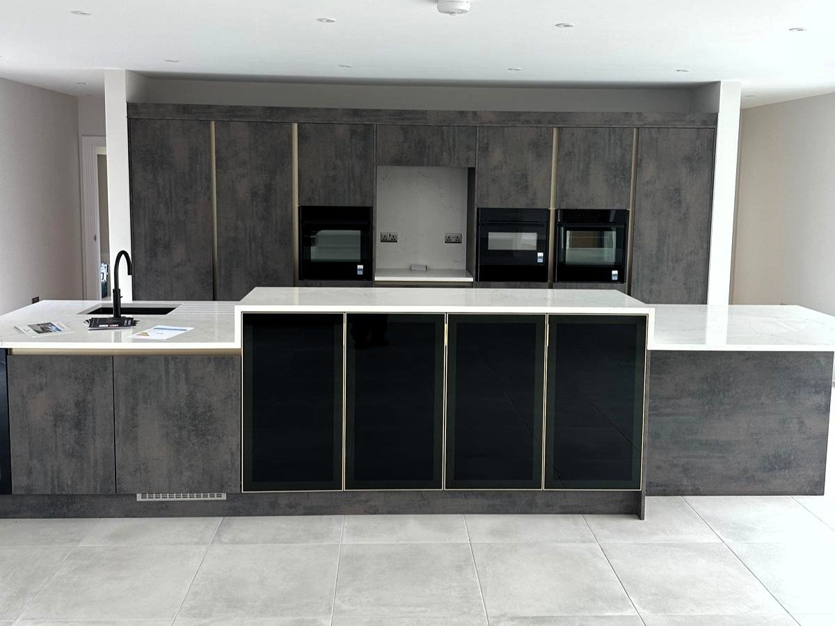 Modern kitchen with black and grey cabinetry, marble countertops, and built-in appliances.