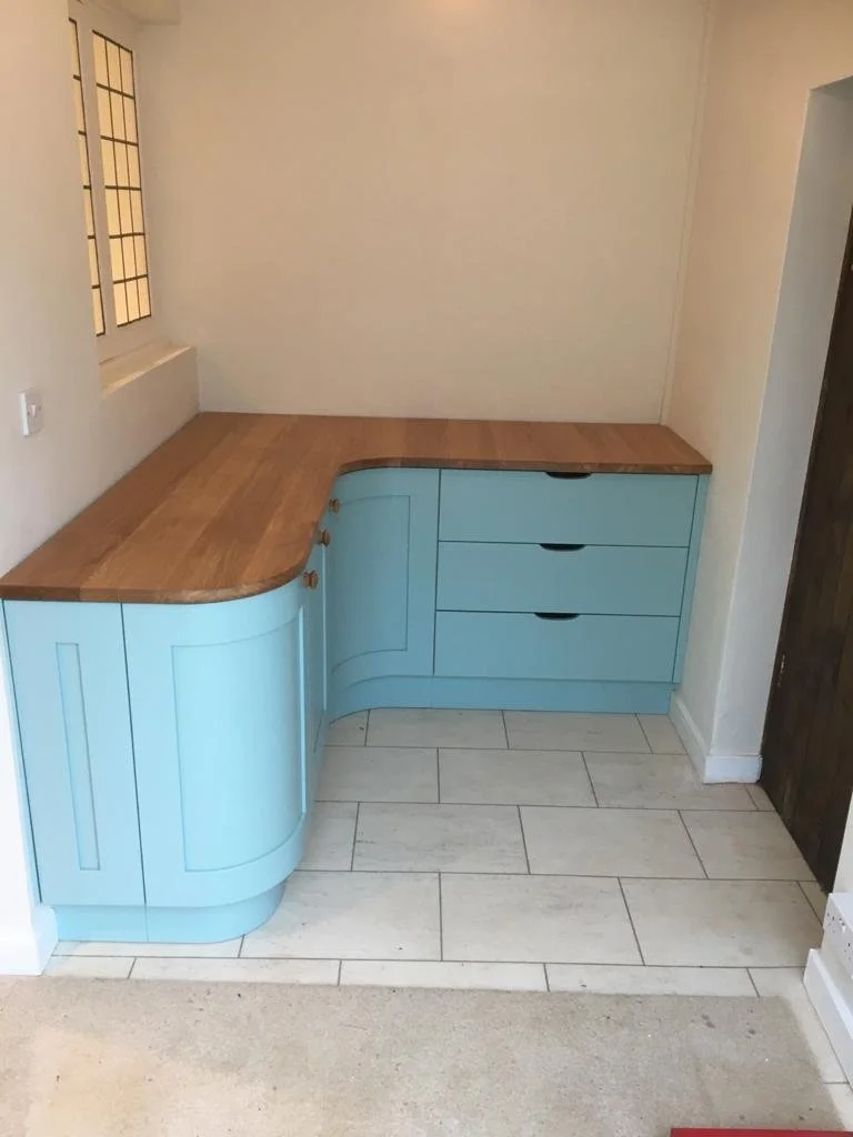 Corner kitchen countertop with light blue cabinets and wooden countertop surface