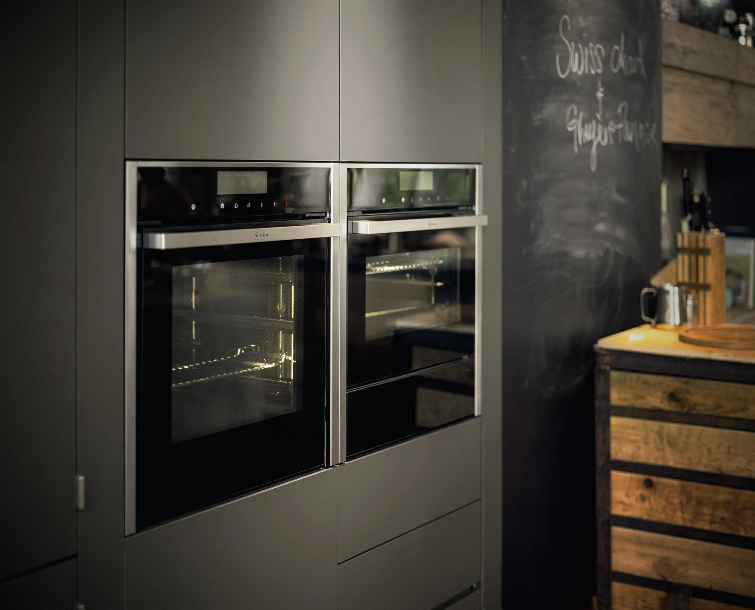 NEFF built-in oven shown in bladark grey cabinetry, adjacent to a chalkboard wall.
