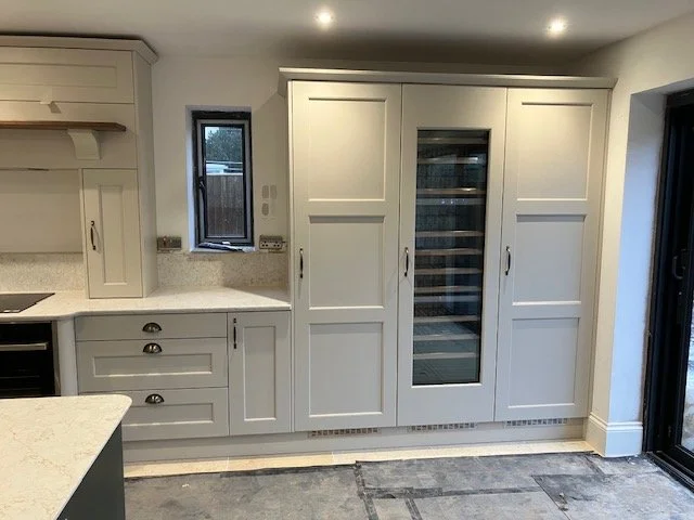 Kitchen with white cabinetry, a small window, and a large built-in wine fridge.