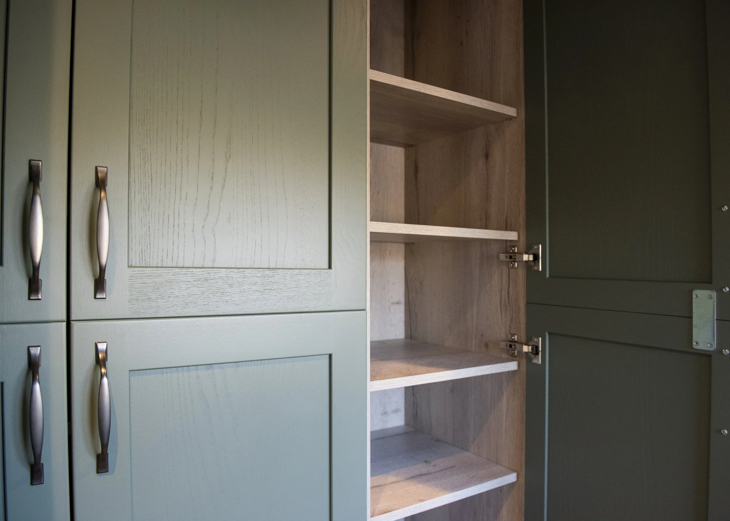 Green cabinet with closed doors on the left and open brown shelving cabinet on the right.