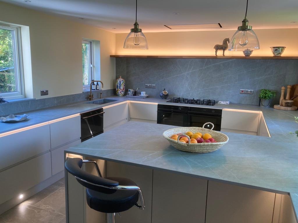 Modern kitchen with grey countertops, white cabinets and black appliances. 