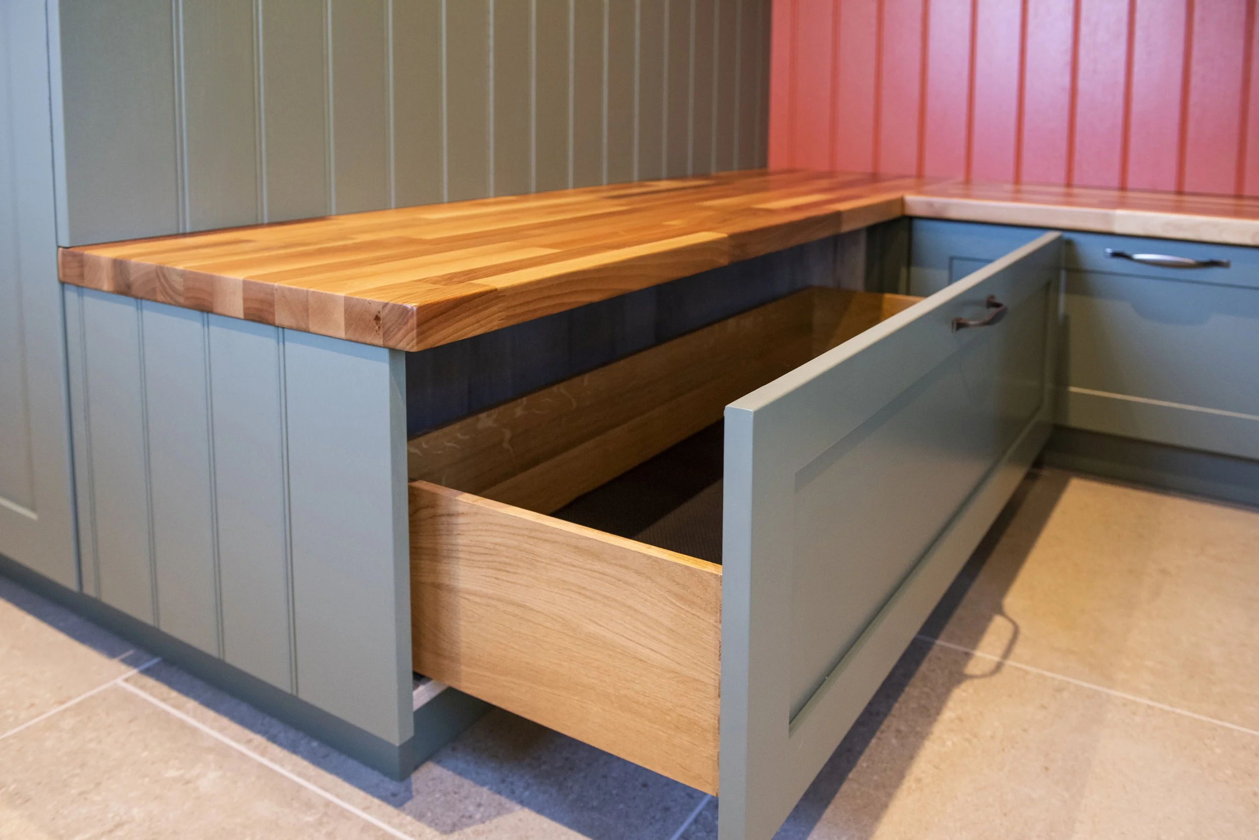 Boot room shoe cabinet with a wooden countertop and green painted doors.