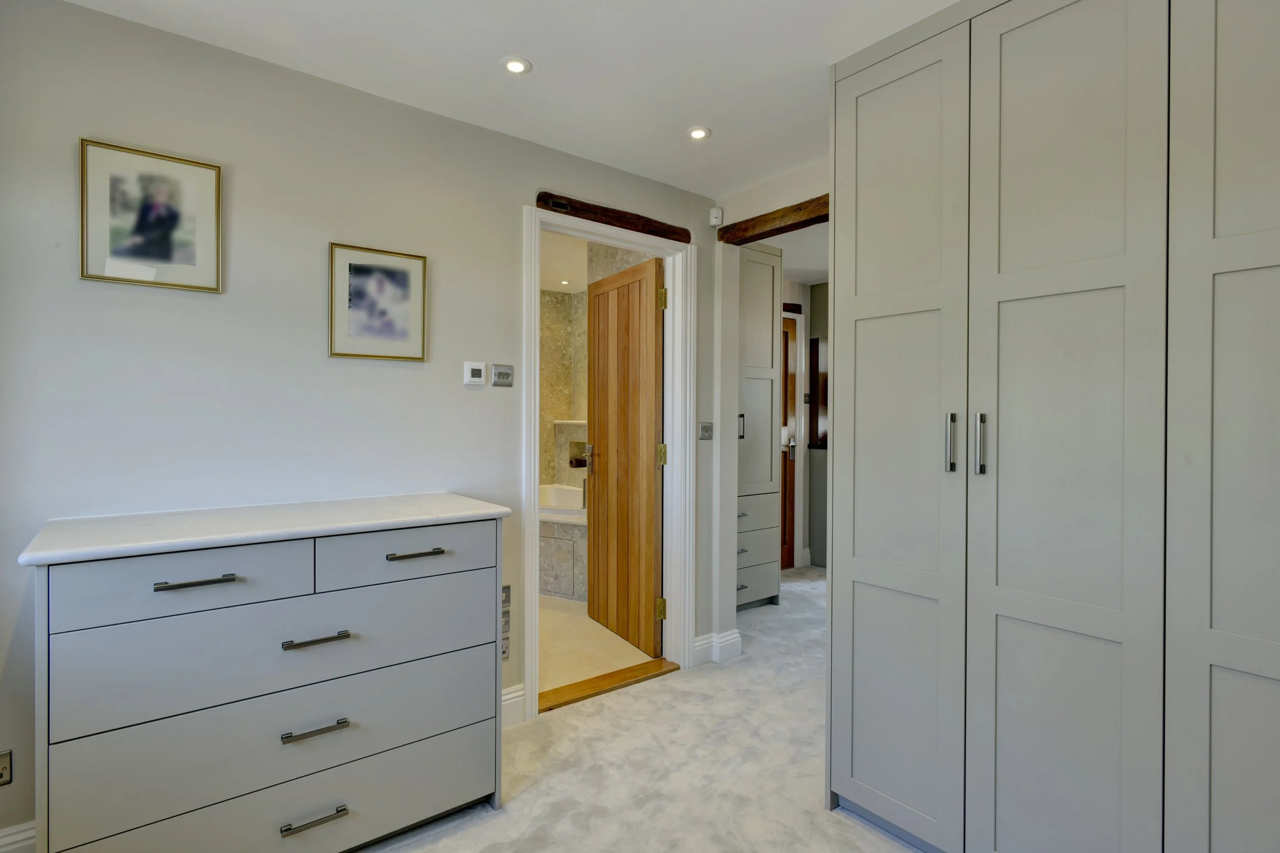 Interior of a modern home with walk in wardrobe, showing a wooden door to a en-suite bathroom.