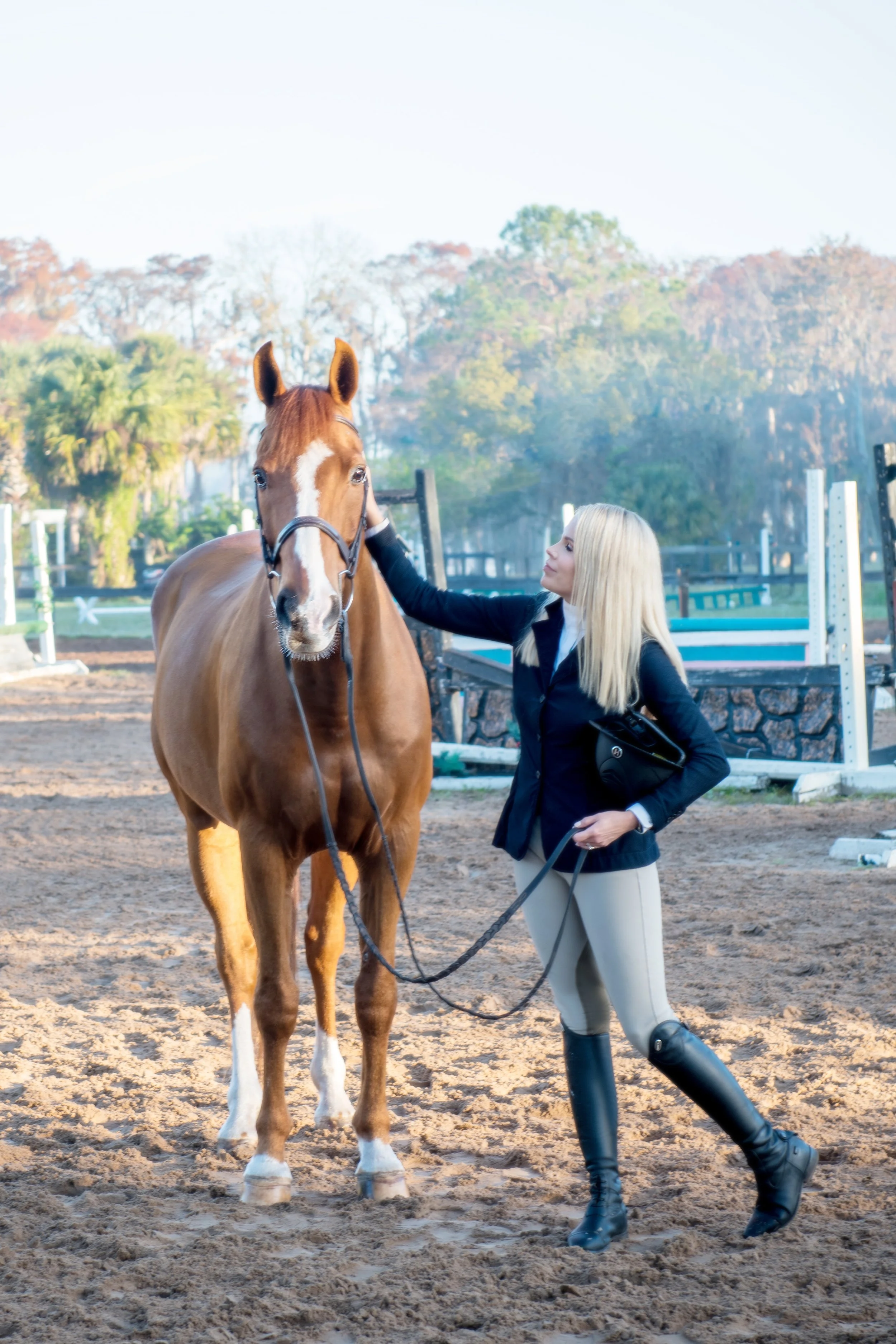 Blonde woman in riding gear petting her horse in Winter Park FL