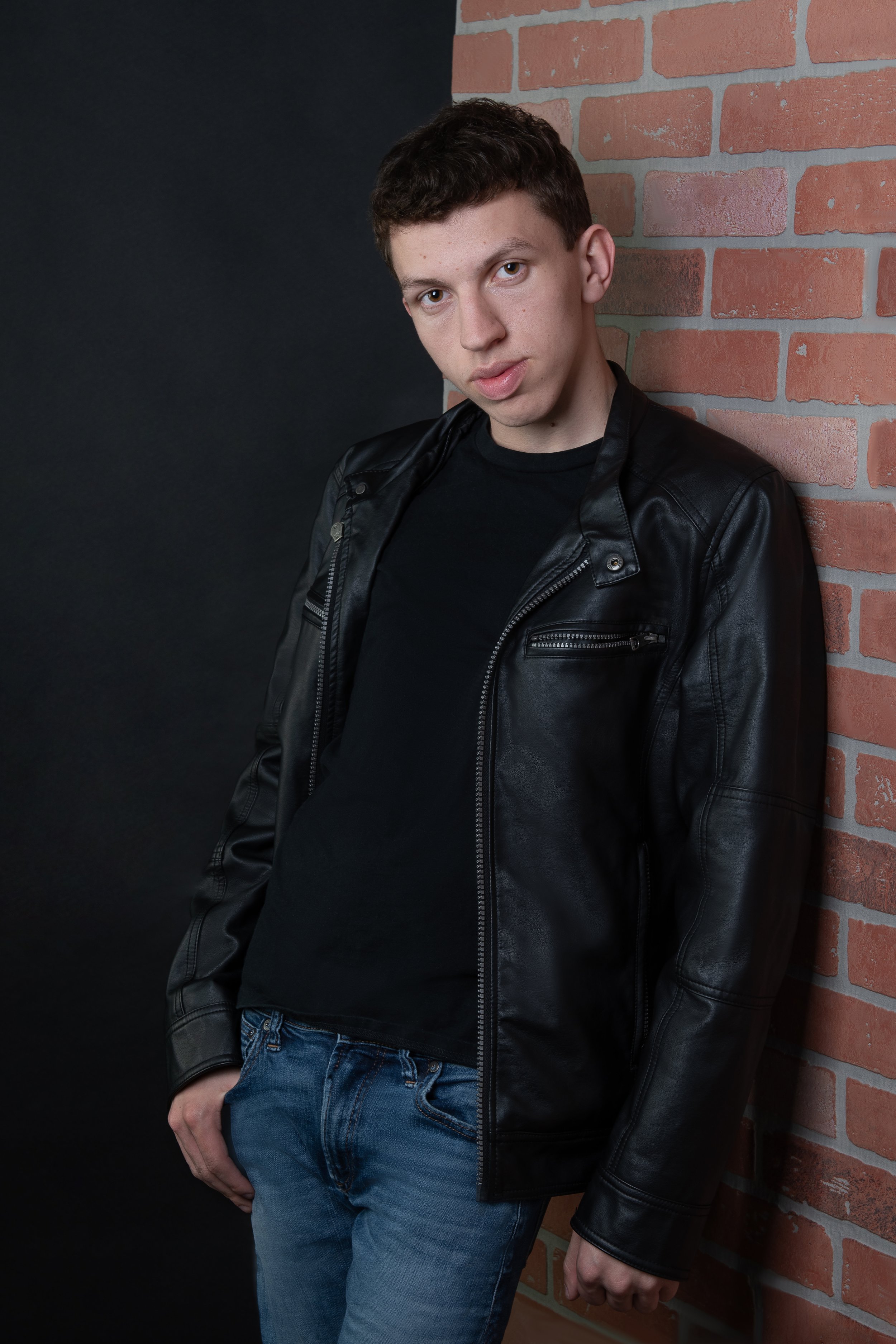 Teen Guy Leather Jacket leaning against brick wall headshot session (Copy)