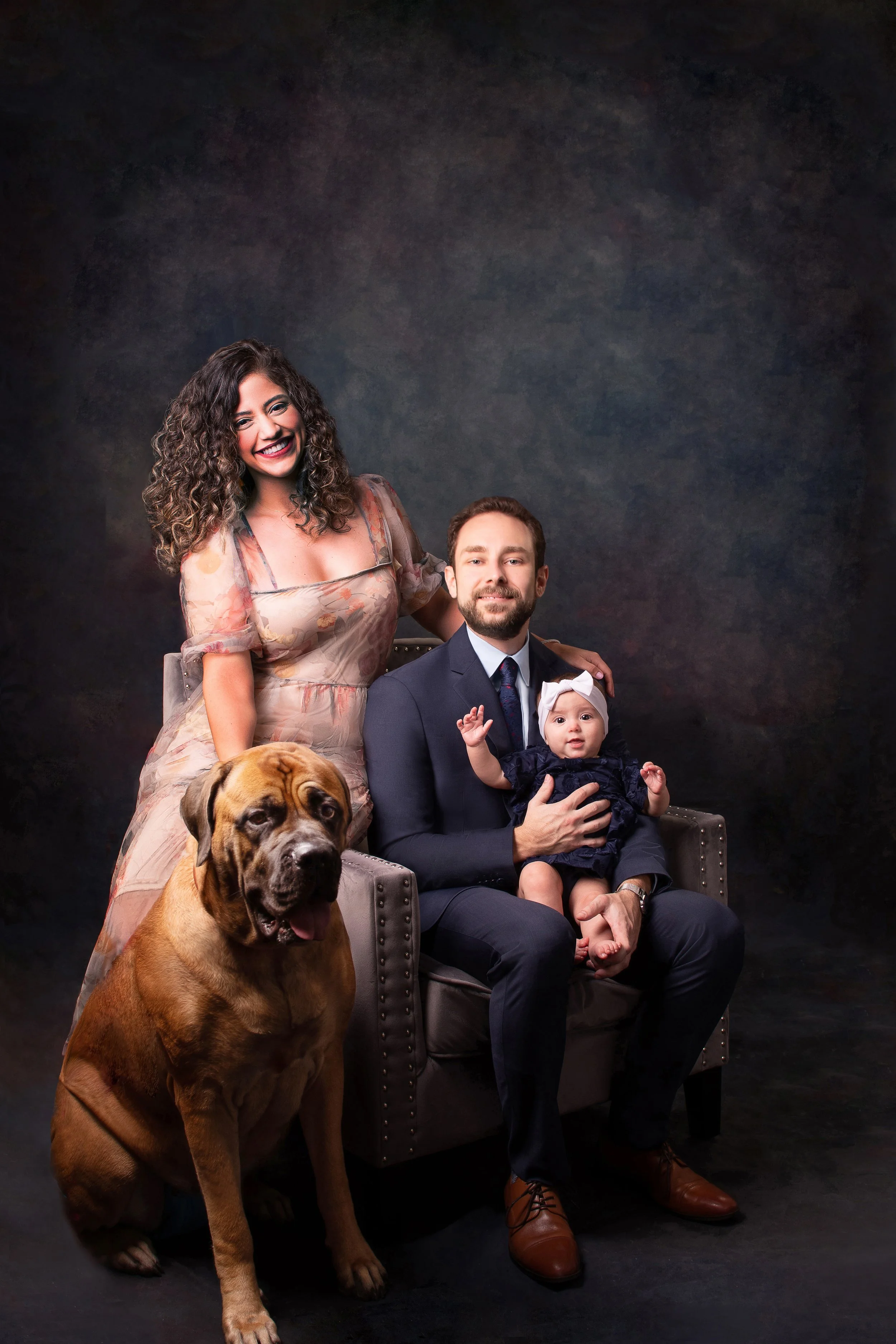 A young family with a baby and a big brown dog pose for family portraits in Winter Park FL