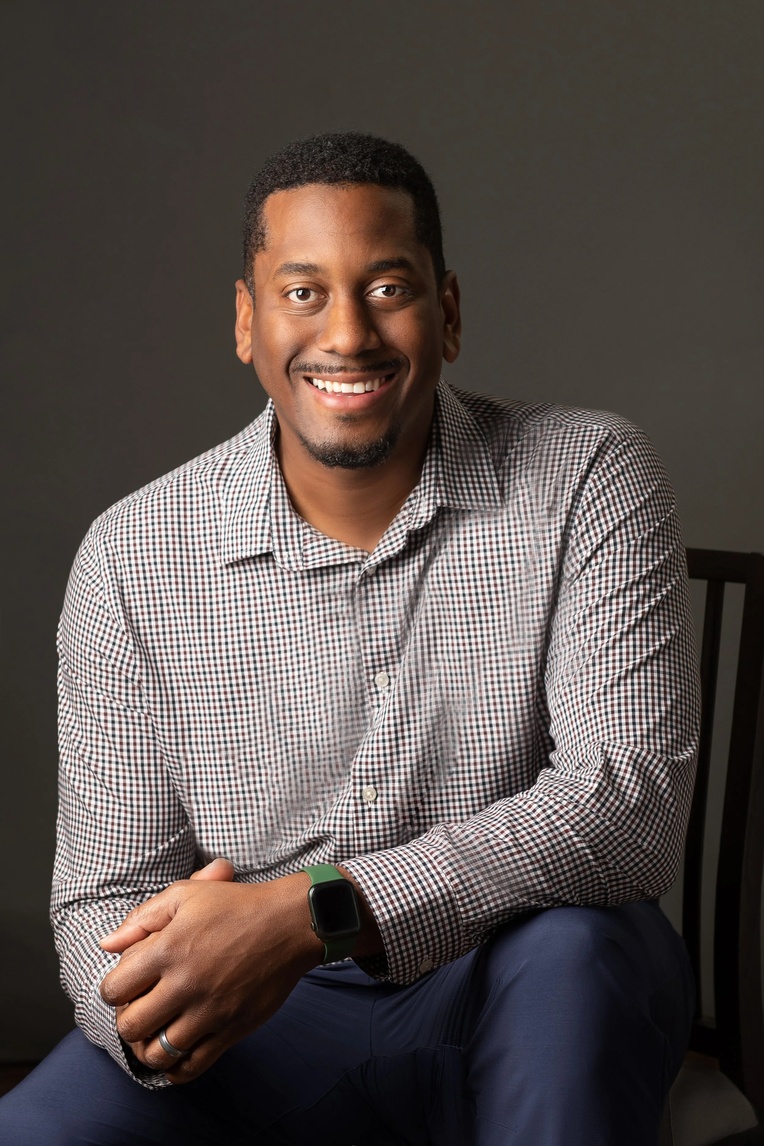 Business Attire Man sitting on wooden chair grey background in studio Portrait headshot