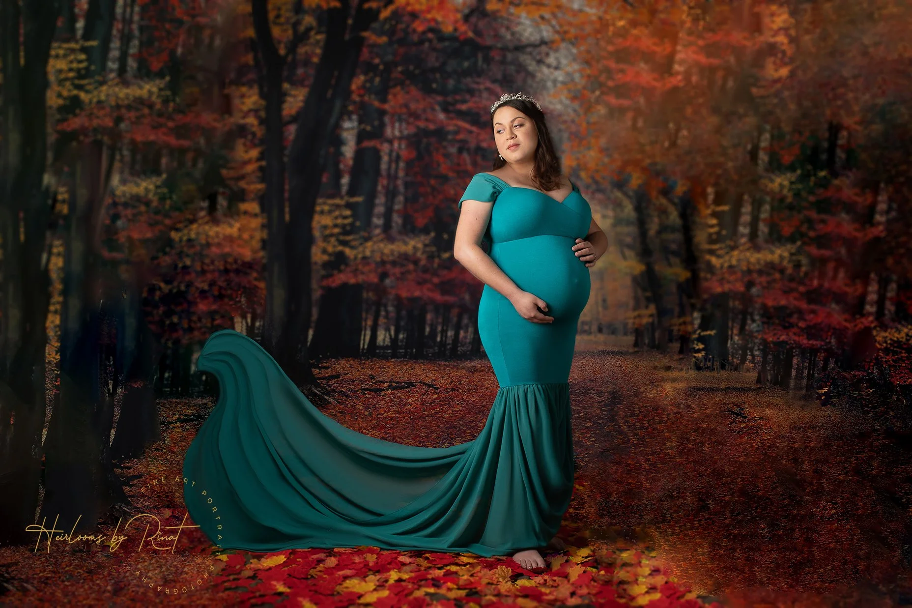 pregnant woman in a teal dress posing against a fall backdrop.
